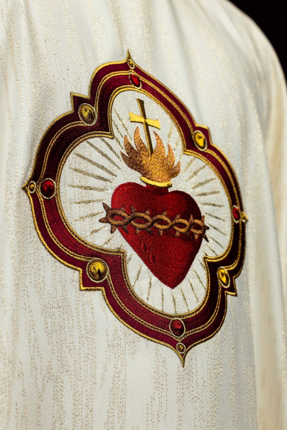 Chasuble close-up showing embroidered Sacred Heart of Jesus with cross and gold rays