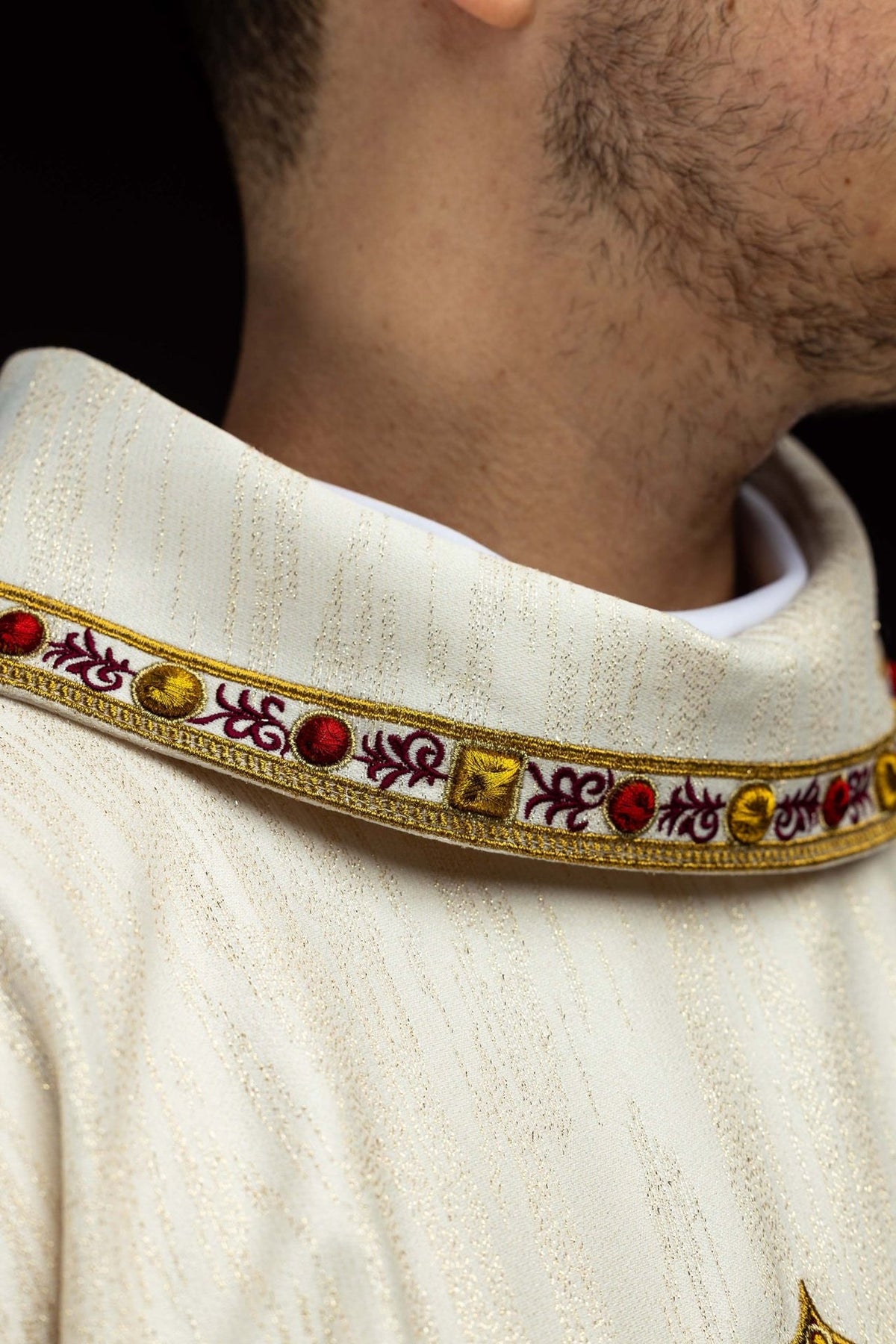 Chasuble close-up showing cream fabric, gold trim and embroidered stand-up collar