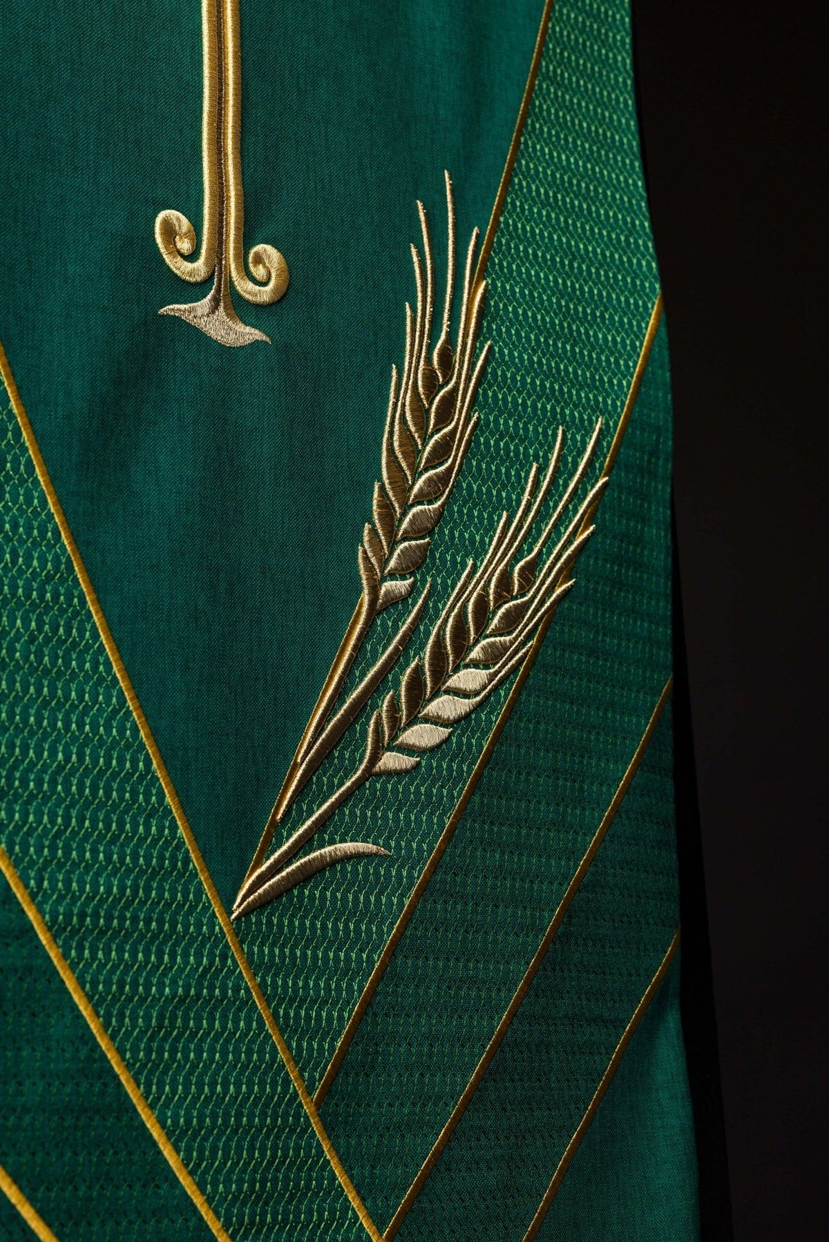 Green church lectern cover close-up showing gold wheat embroidery and patterned bands