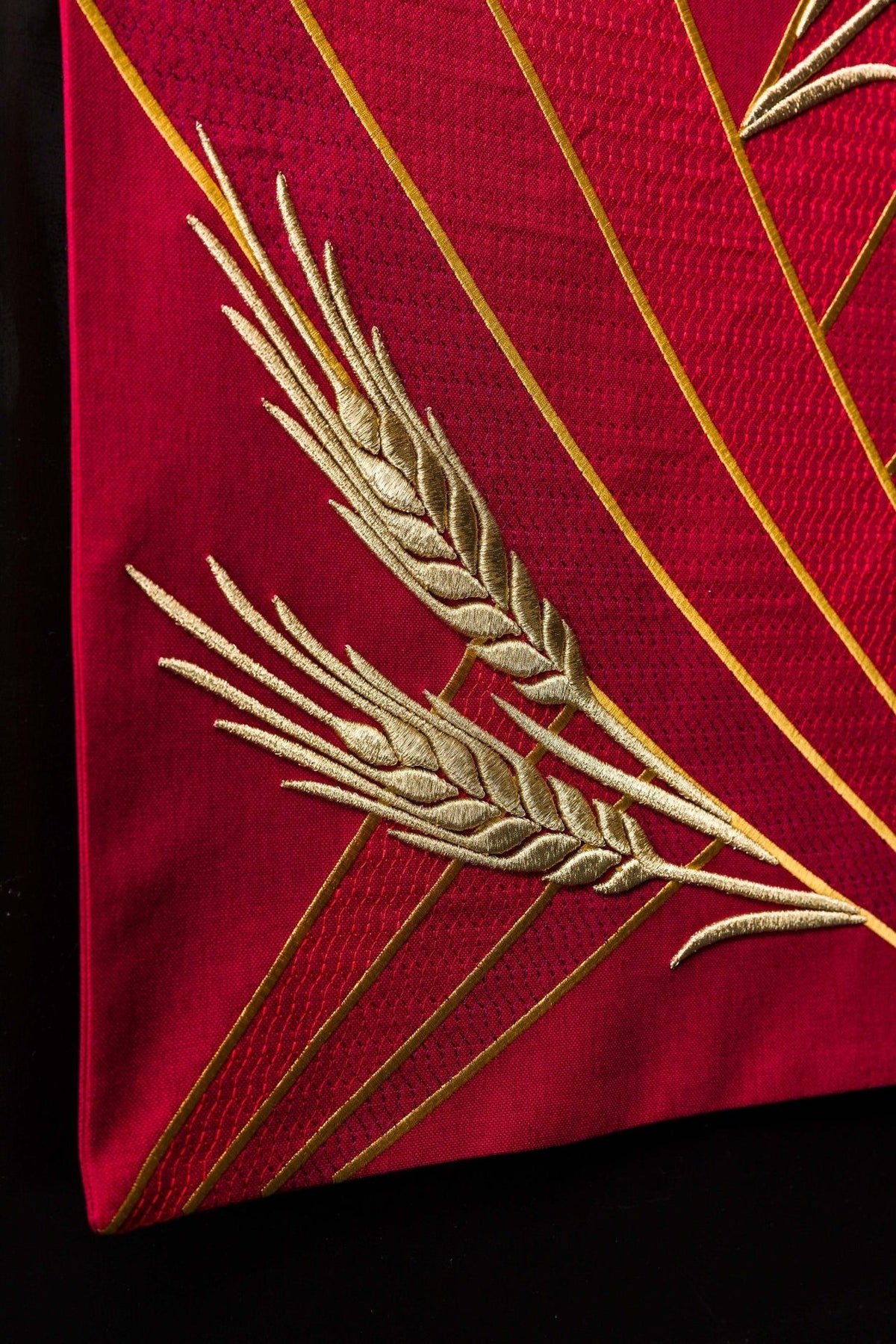 Red church lectern cover detail with crossed gold wheat embroidery and diagonal lines