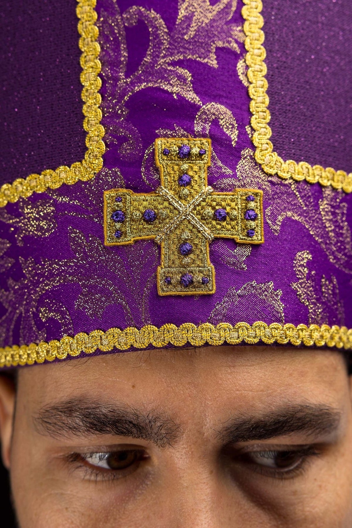 Purple miter close-up showing embroidered gold cross and gold trim