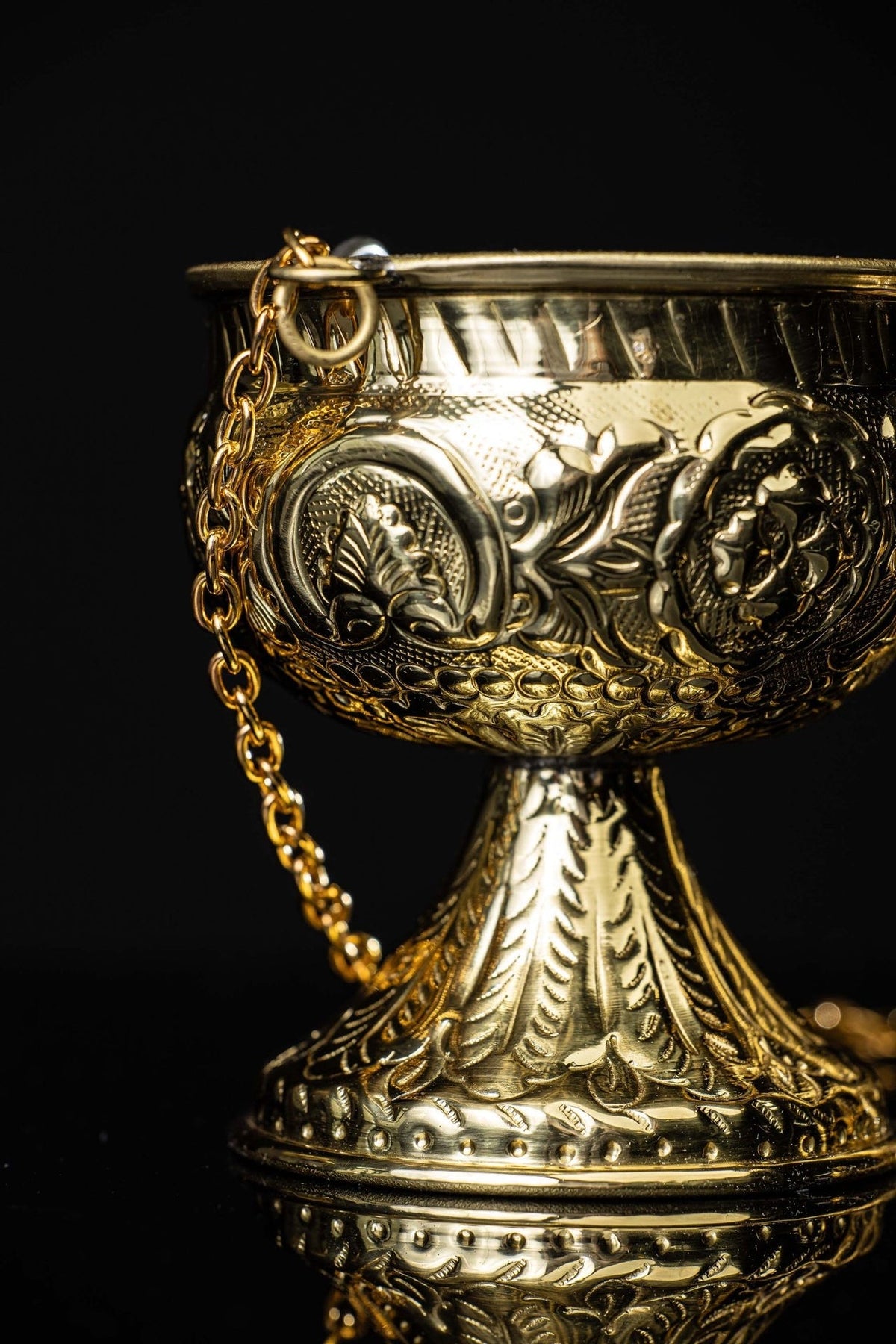 Brass thurible bowl close-up with floral medallions and chain attachment