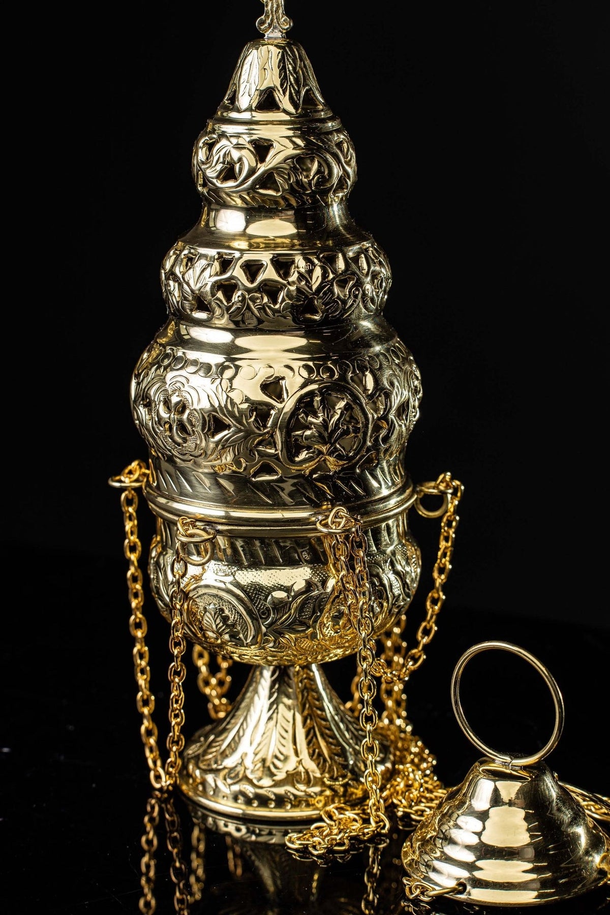 Brass thurible close-up showing embossed floral body and chains