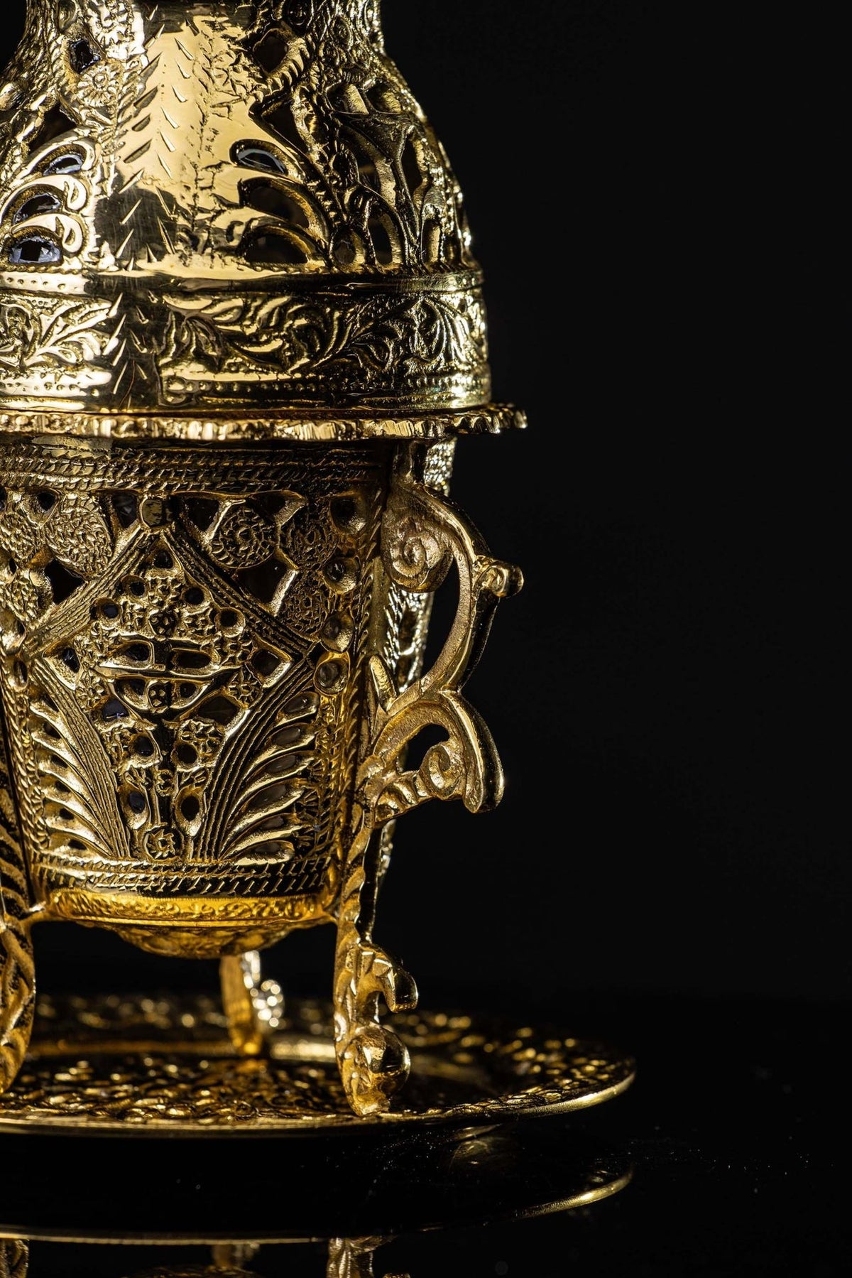 Gold censer side close-up showing pierced floral body and curled stand detail