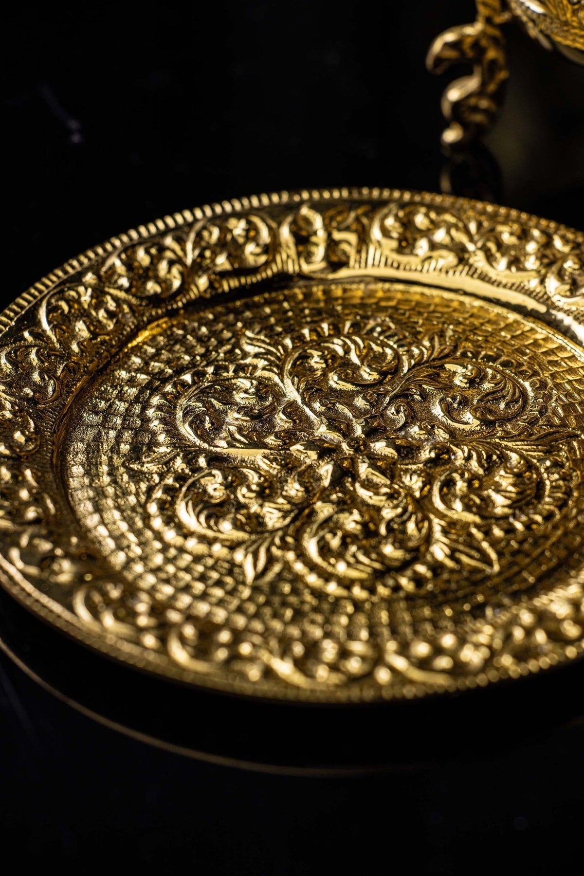 Gold censer stand plate close-up with raised floral scrollwork
