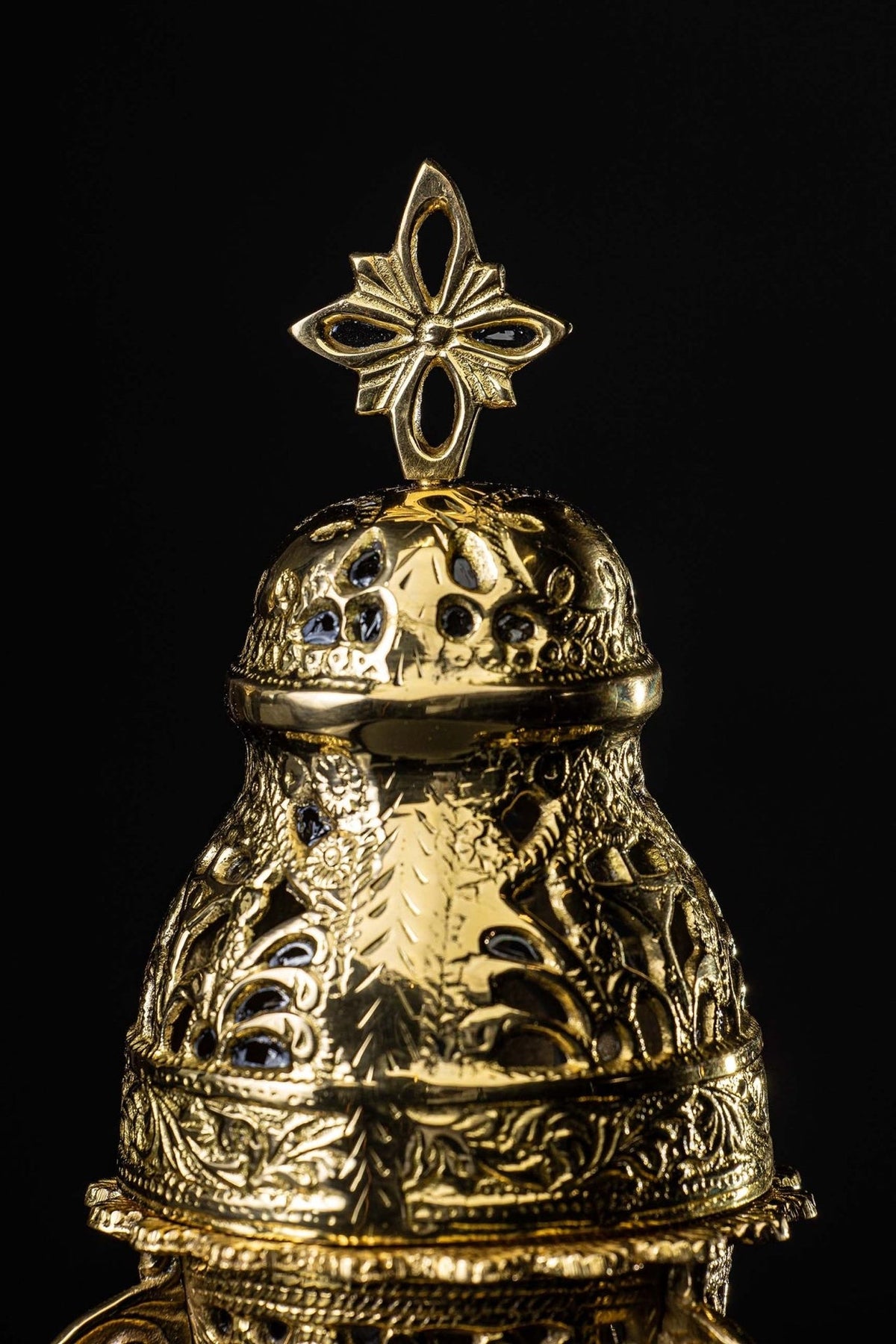 Gold censer lid close-up with pierced floral motifs and cross