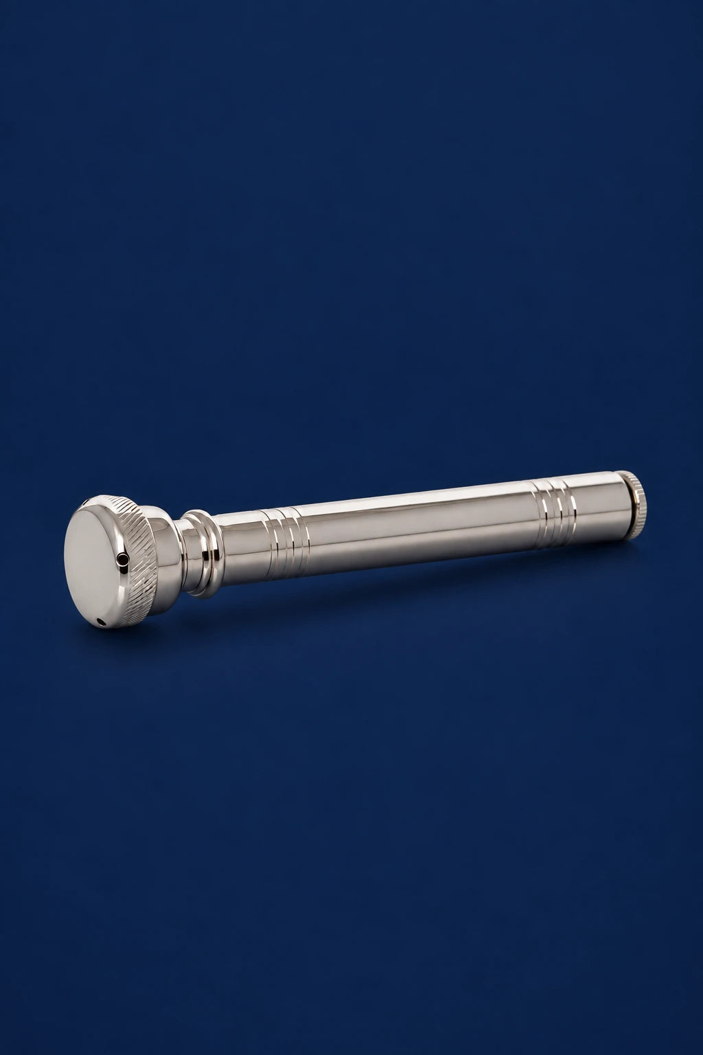 Nickel-plated brass aspergillum, side view with round perforated head and long cylindrical handle