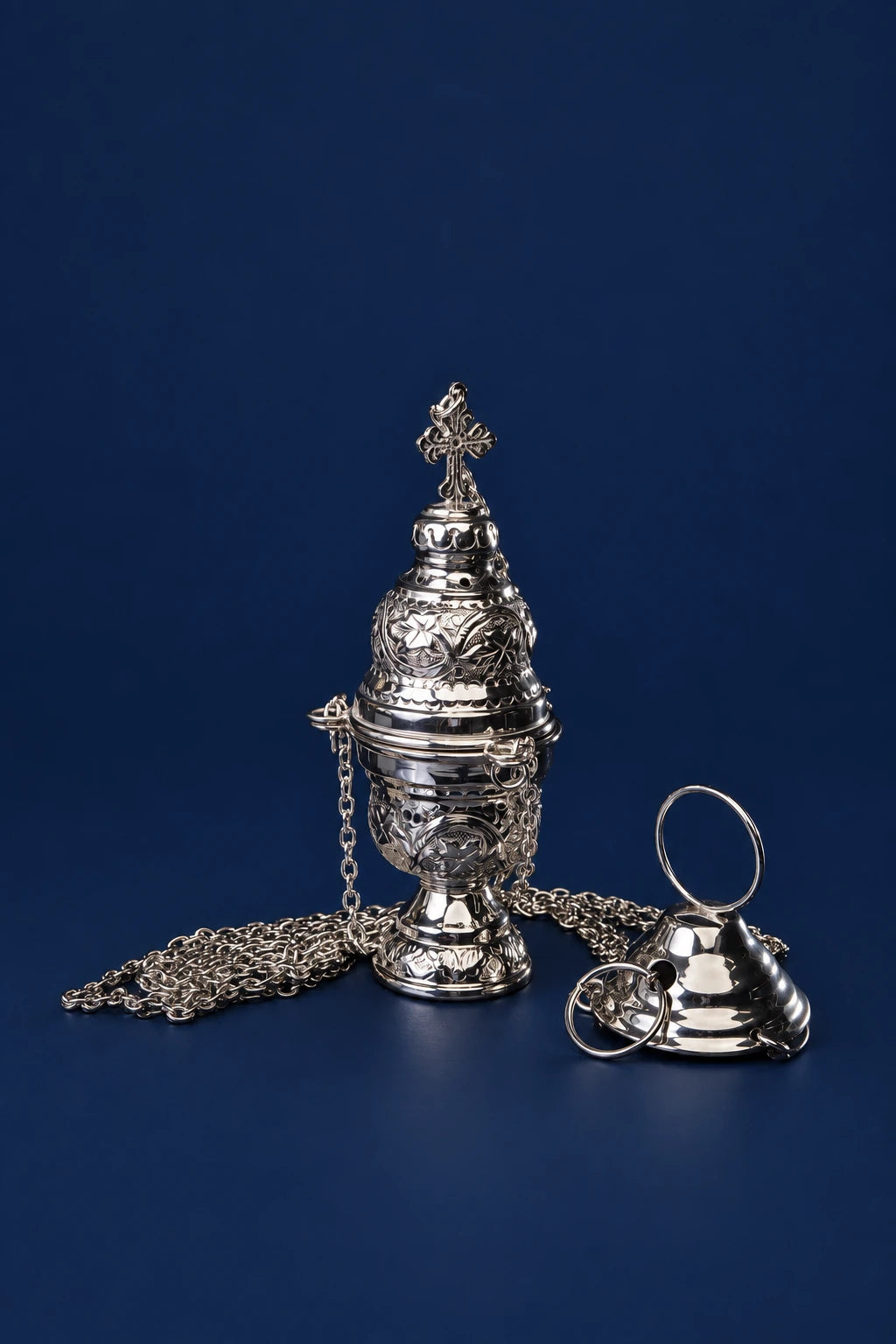 Nickel-plated brass thurible with cross finial, shown front view with chain and lid beside it