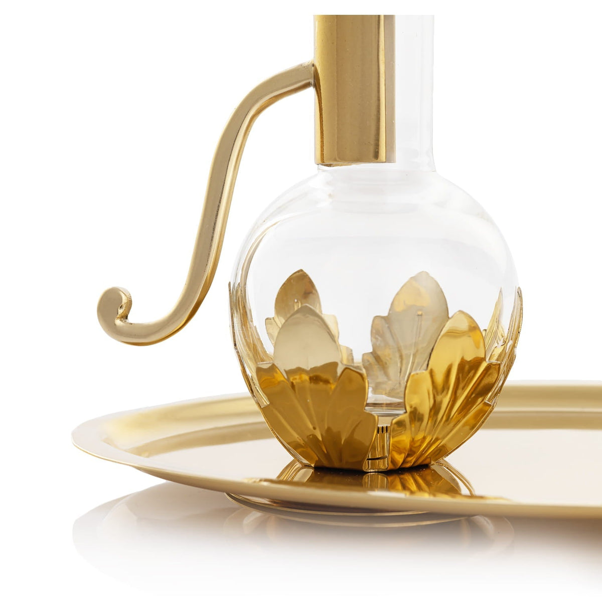 Brass cruet close-up showing curved handle, clear glass and layered leaf motifs