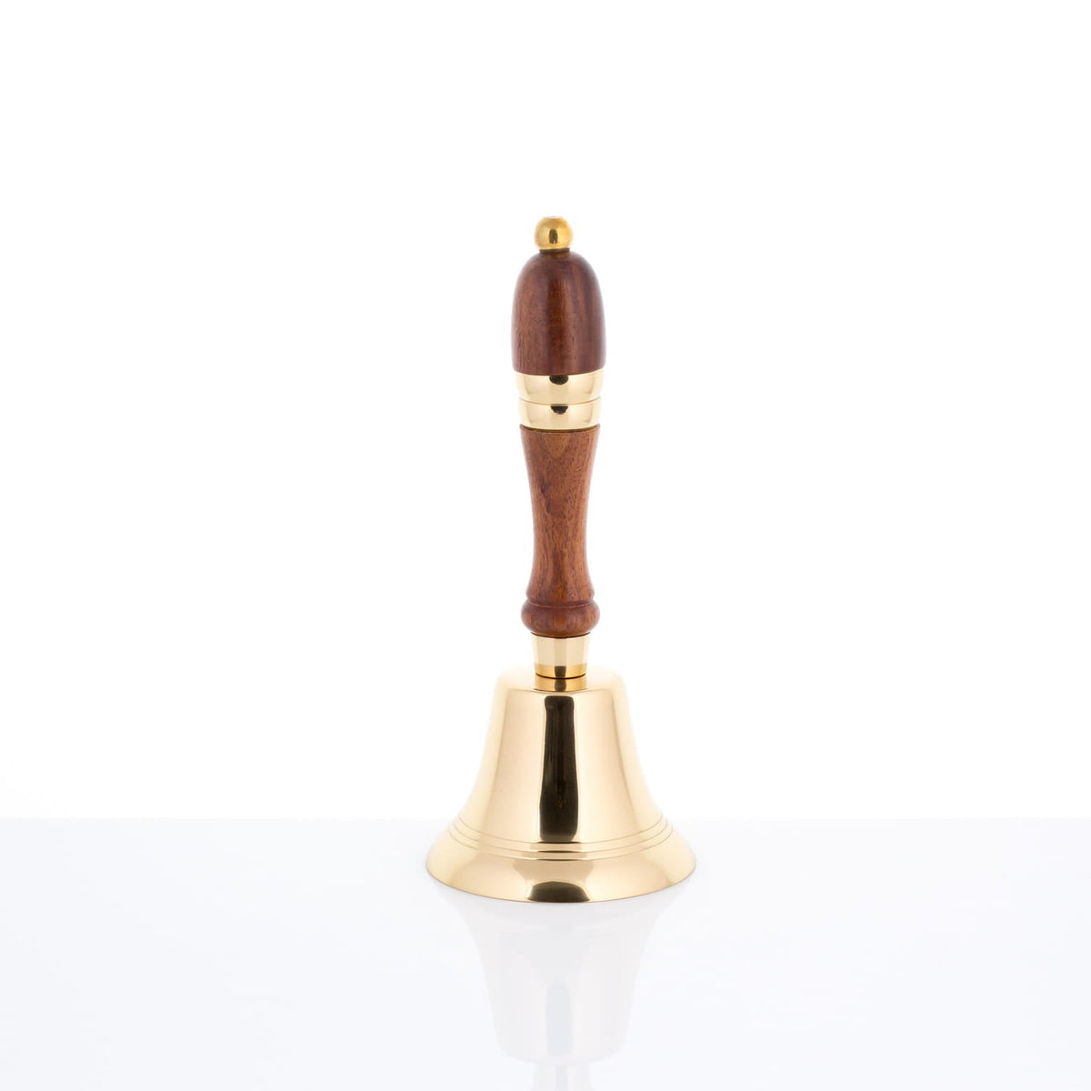 Brass altar bell standing upright with polished brass bell and wooden handle