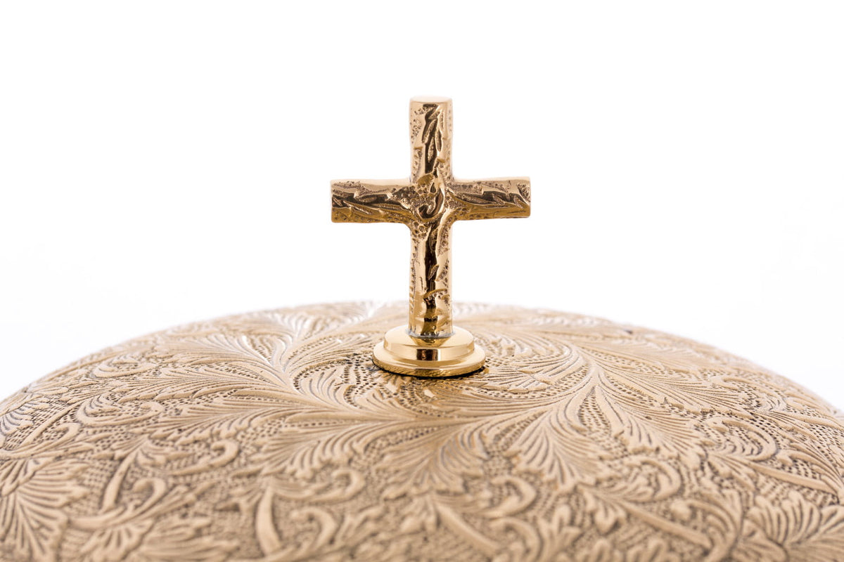 Brass altar bells close-up showing the engraved dome and raised cross