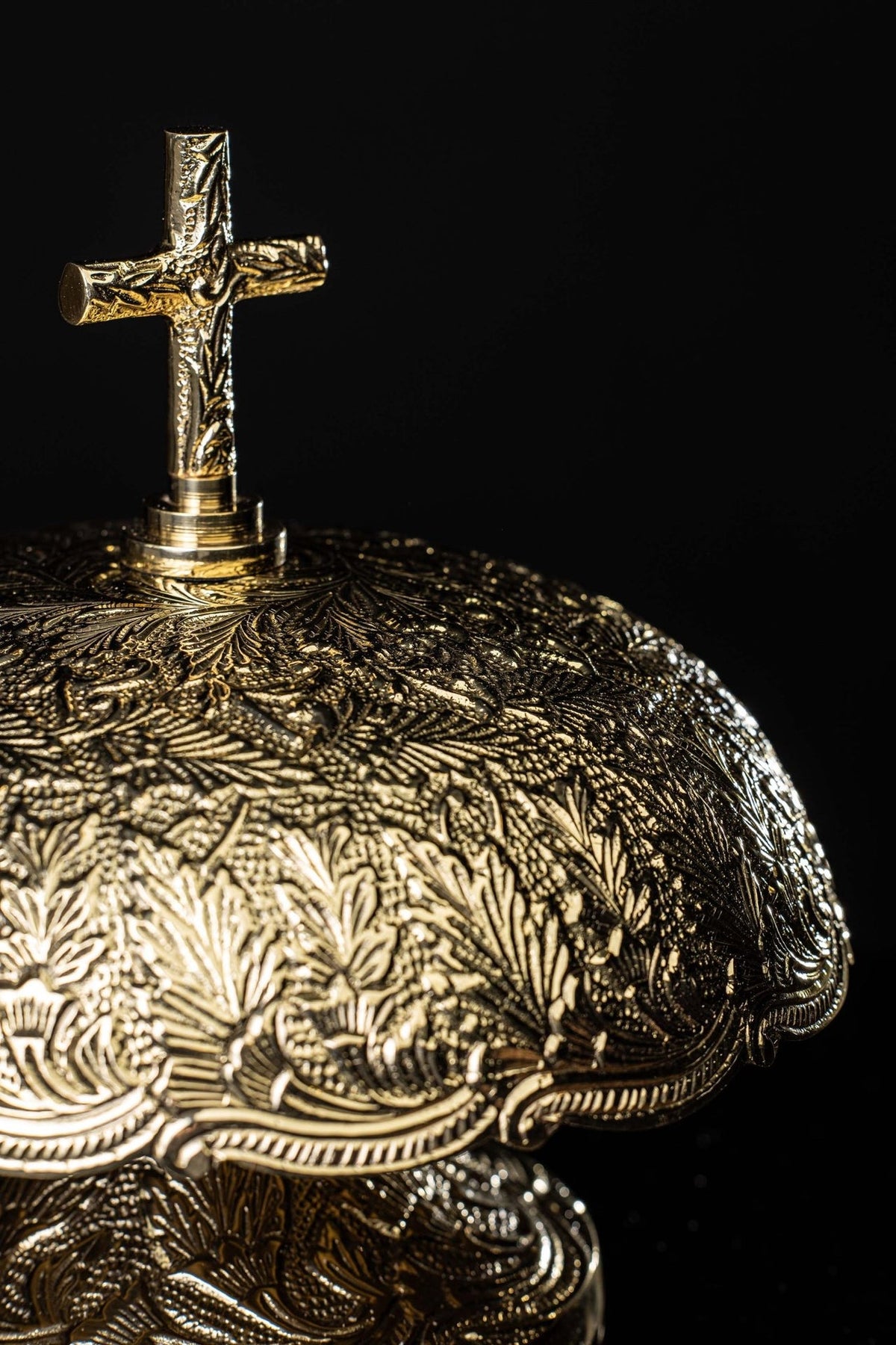 Brass altar bells, close-up of ornate domed top and cross