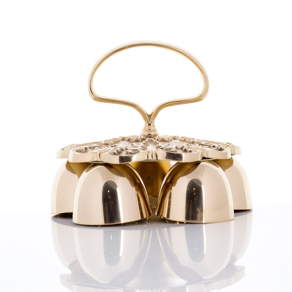 Brass altar bells close-up showing four polished bells and ornate floral lid