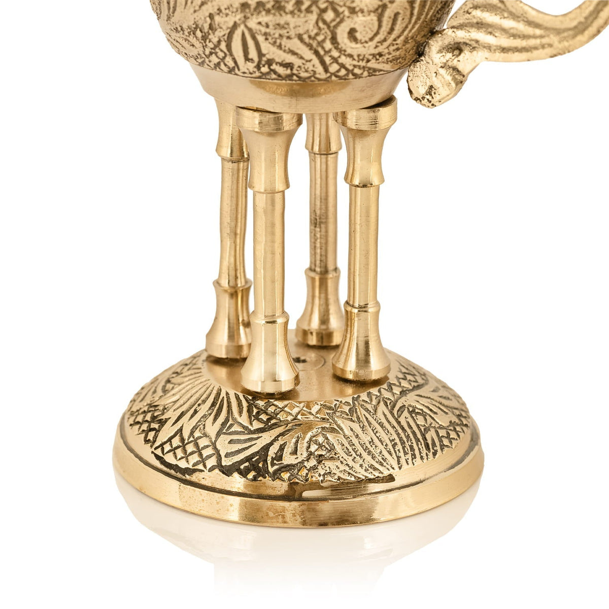 Brass censer close-up showing engraved base and four supporting legs
