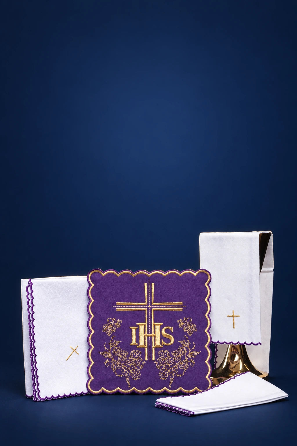 Purple embroidered altar linen set with IHS cross, shown front view with folded white linens and chalice veil