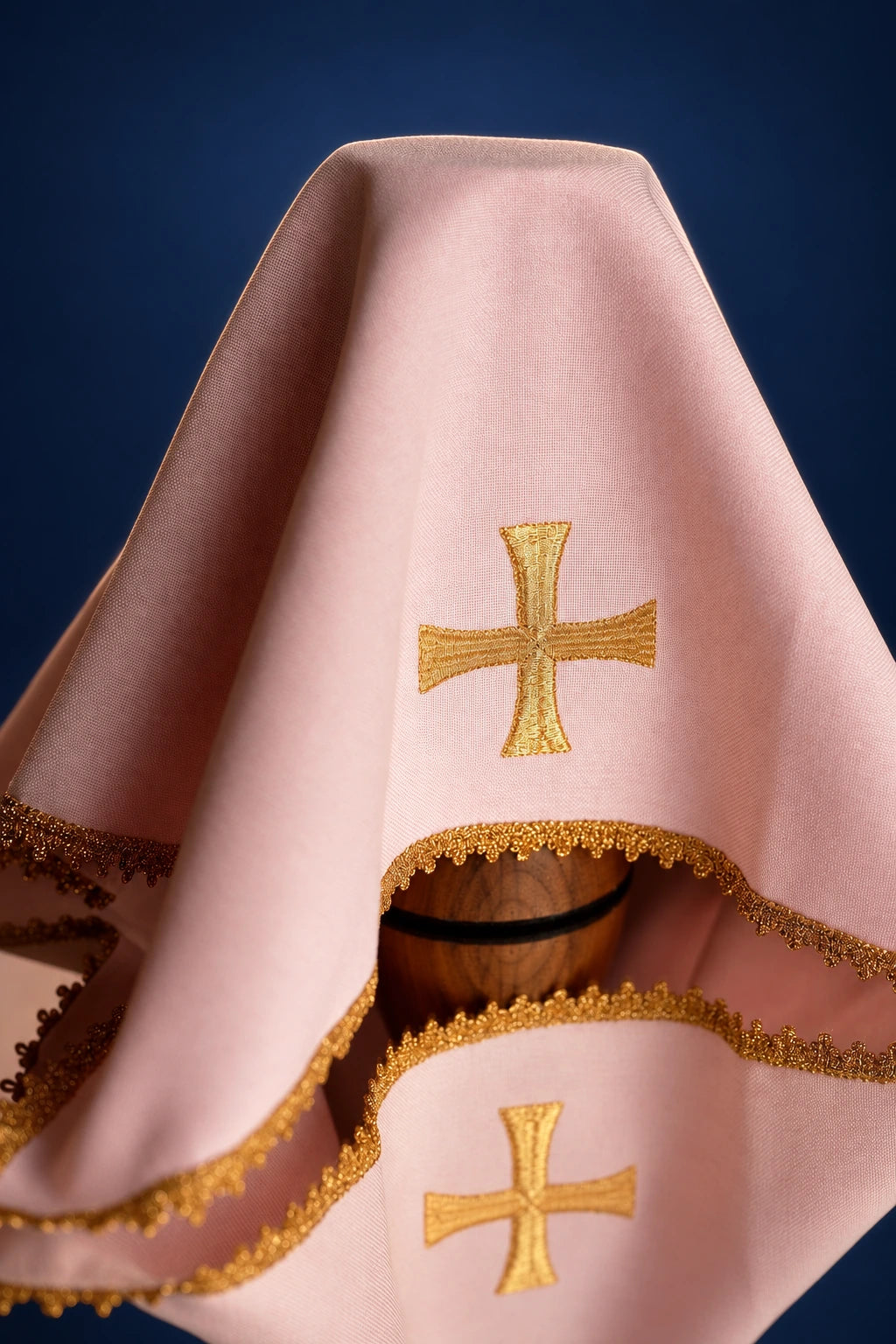 Rose chalice veil draped over a chalice, with gold cross embroidery and gold-trimmed edges