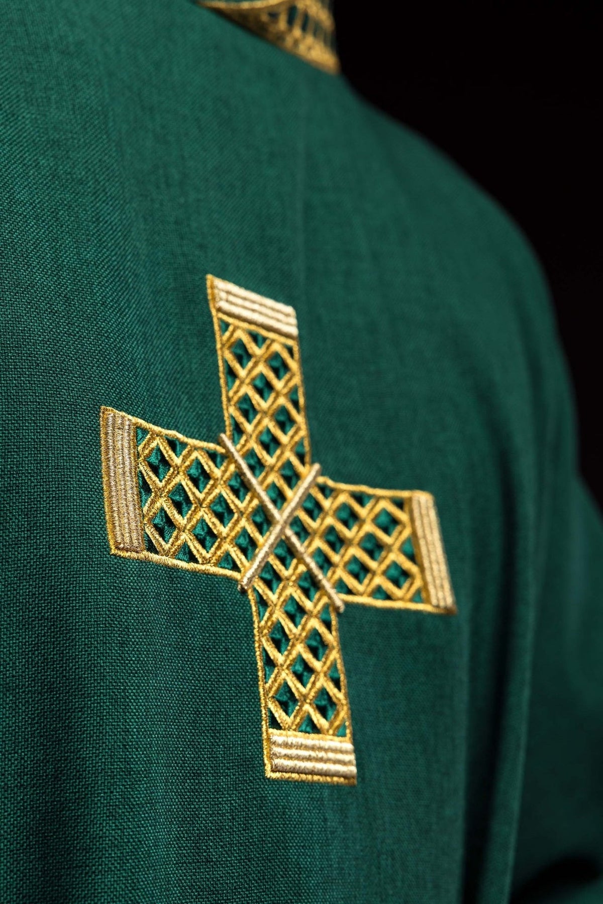 Green dalmatic close-up of gold embroidered cross on green fabric