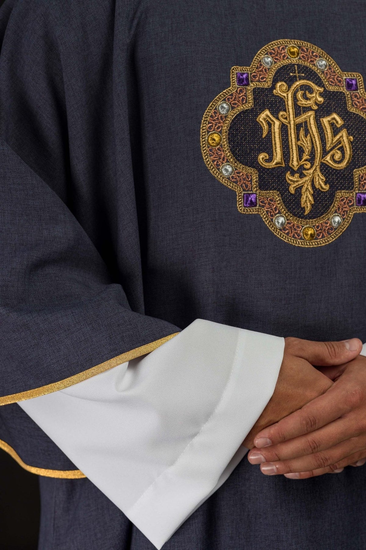 Purple dalmatic close-up showing embroidered IHS symbol and gold sleeve trim