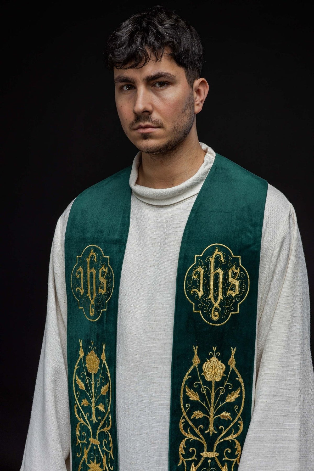 Green stole close-up showing embroidered floral panel, gold trim and tassels