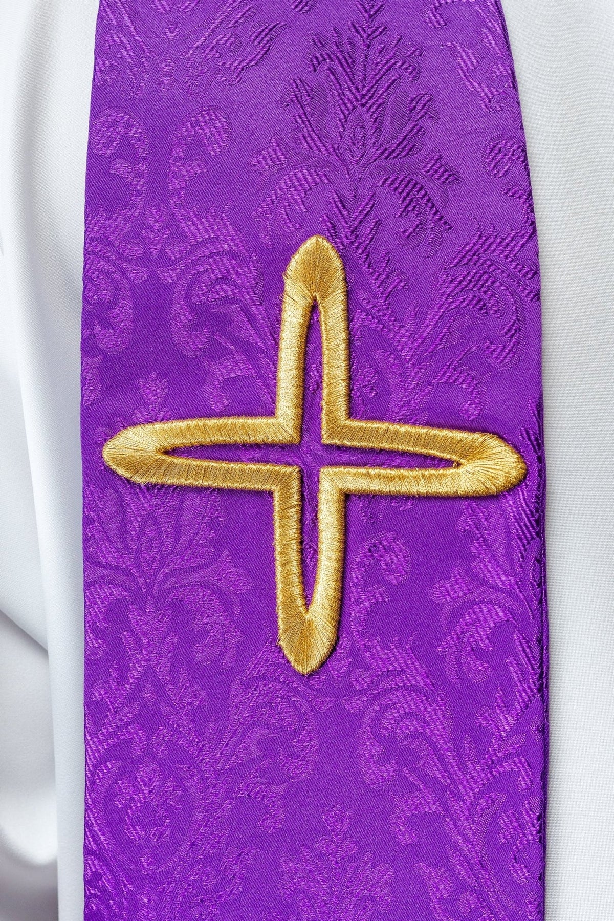 Purple stole close-up showing a large gold cross embroidery on jacquard fabric