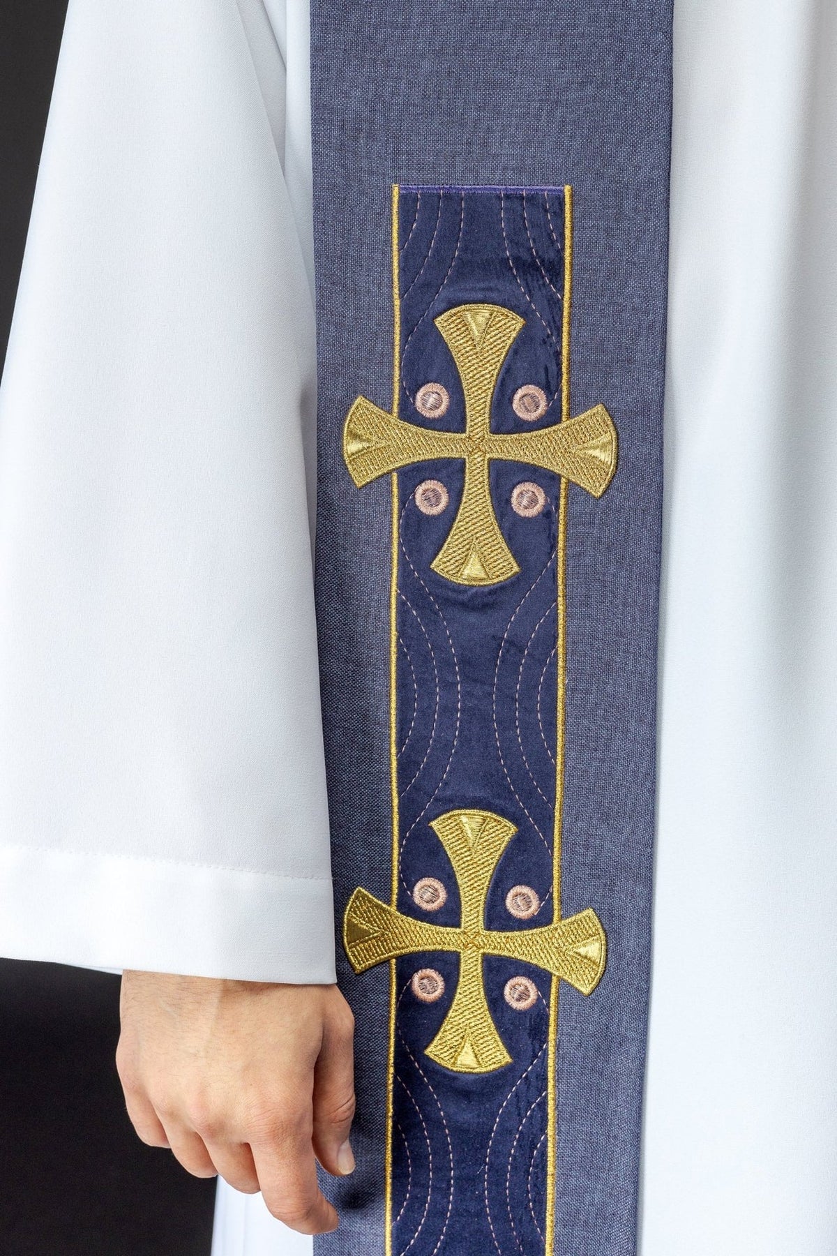 Purple stole close-up showing gold cross embroidery, pink accents and stitched detailing