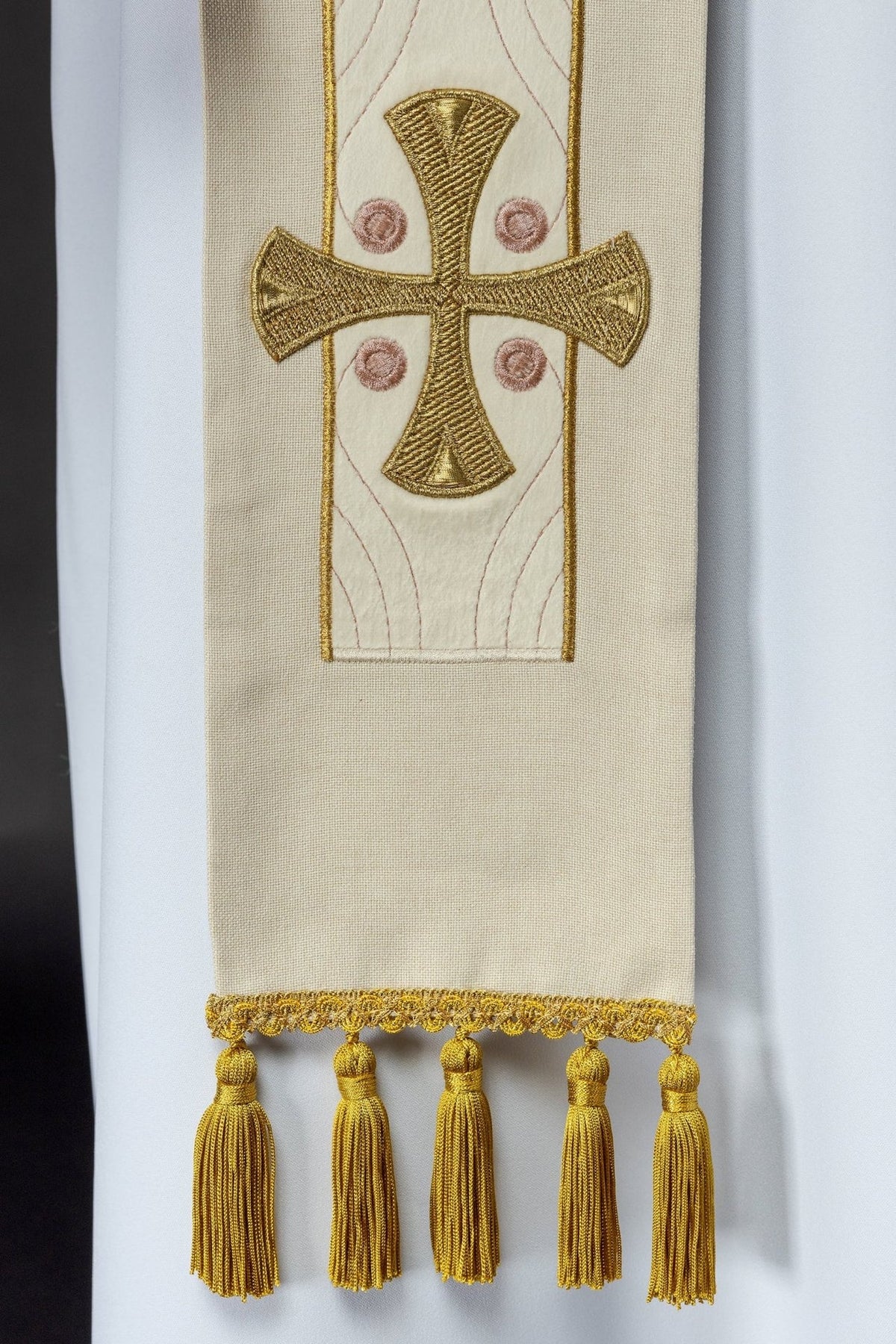 Ecru stole detail showing a gold embroidered cross and tasselled end