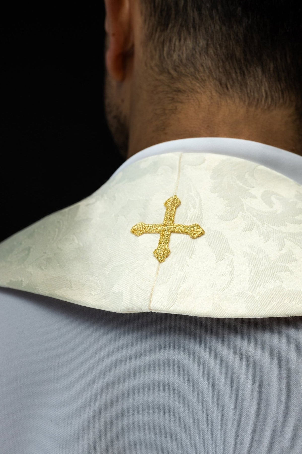 Ecru stole worn from the side, showing Paschal Lamb embroidery and gold trim