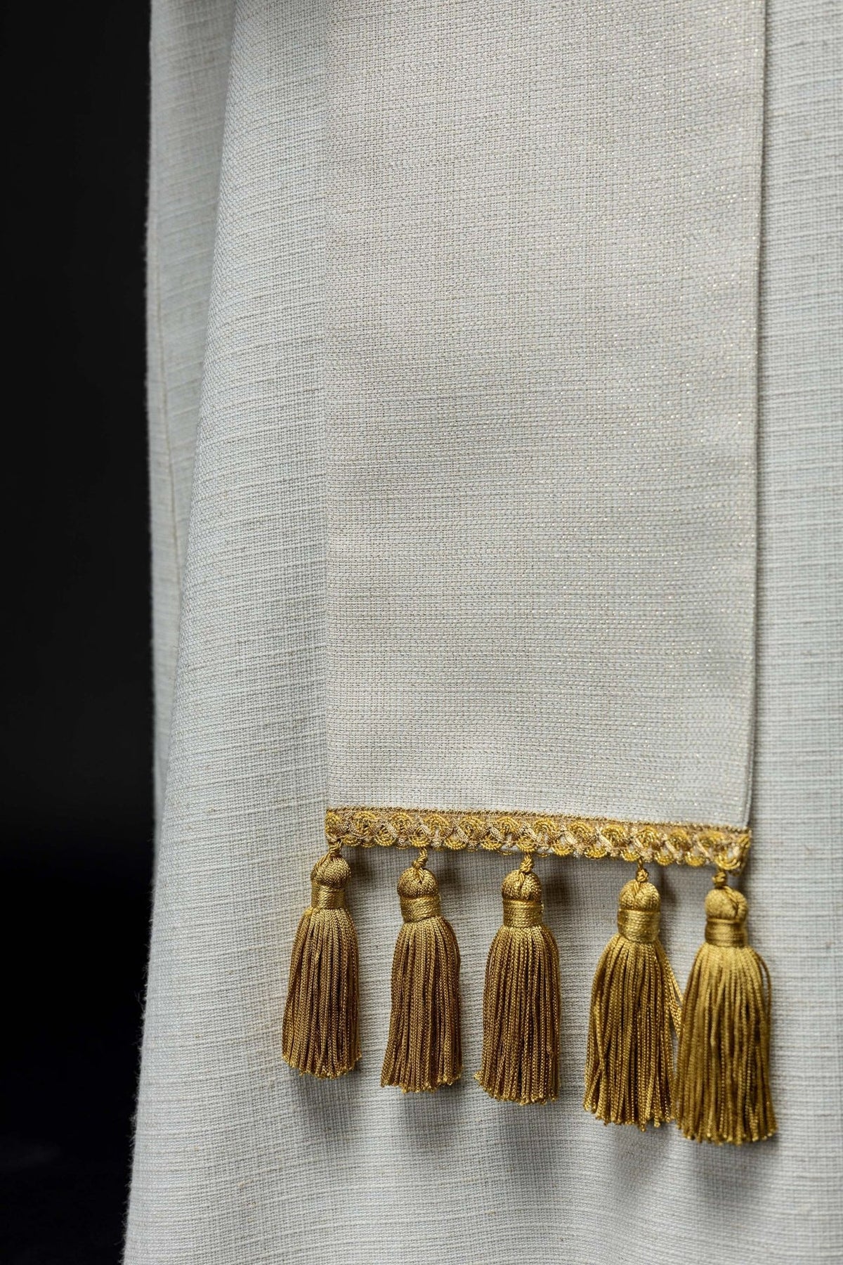 Ecru stole close-up showing gold tassel fringe and ecru fabric
