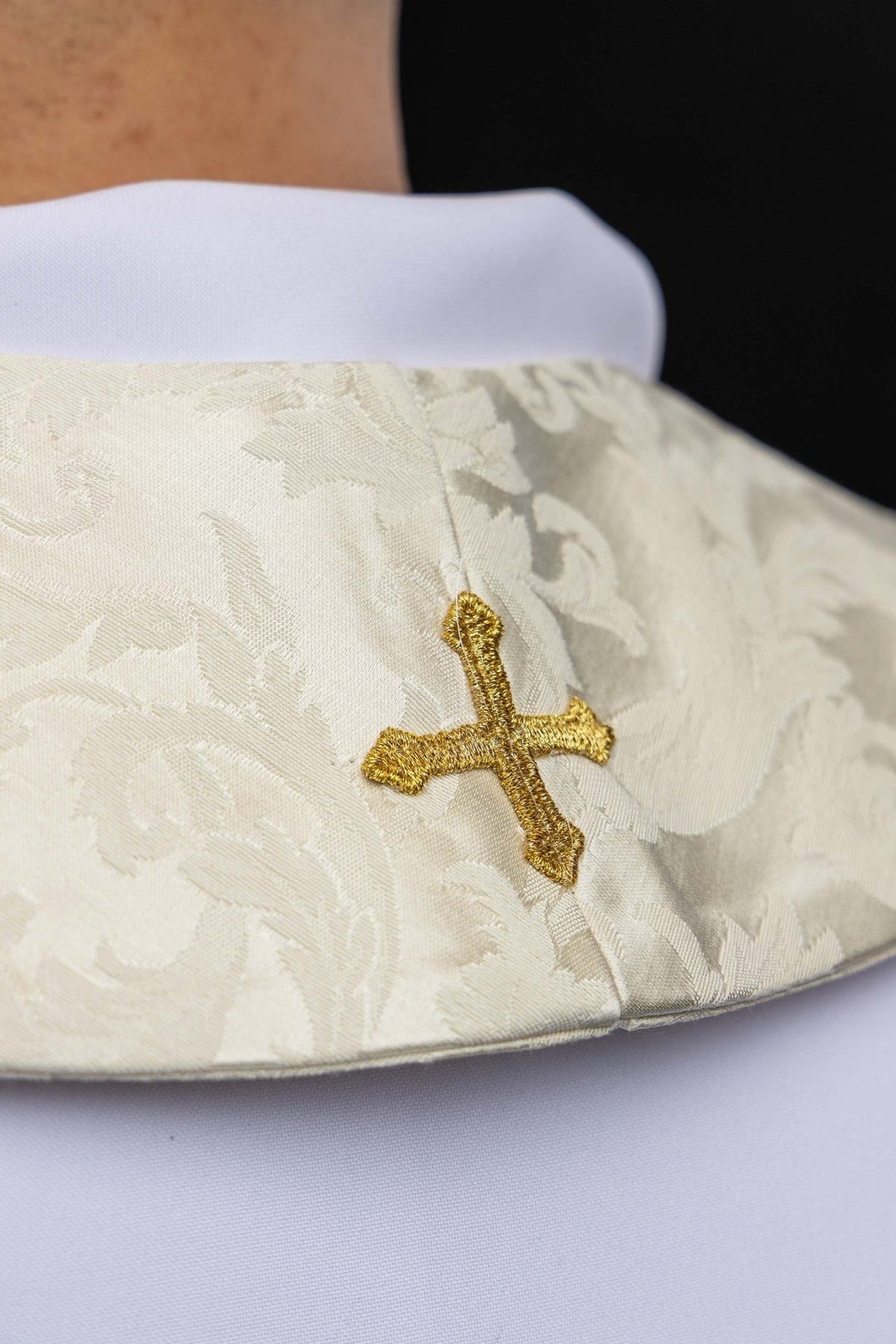 Stole close-up showing gold embroidered cross on ecru jacquard fabric