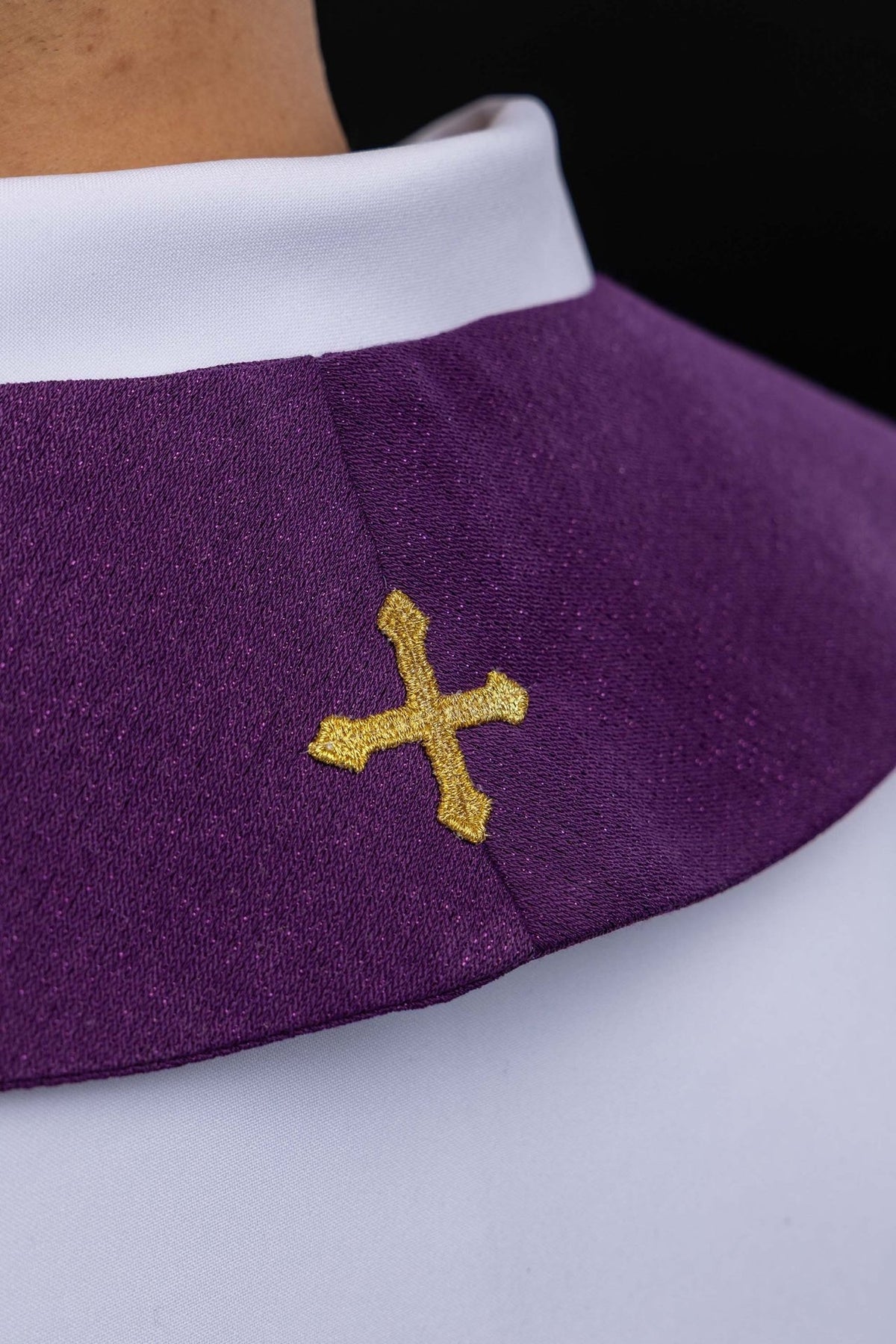 Purple stole close-up showing shimmering fabric and small gold embroidered cross