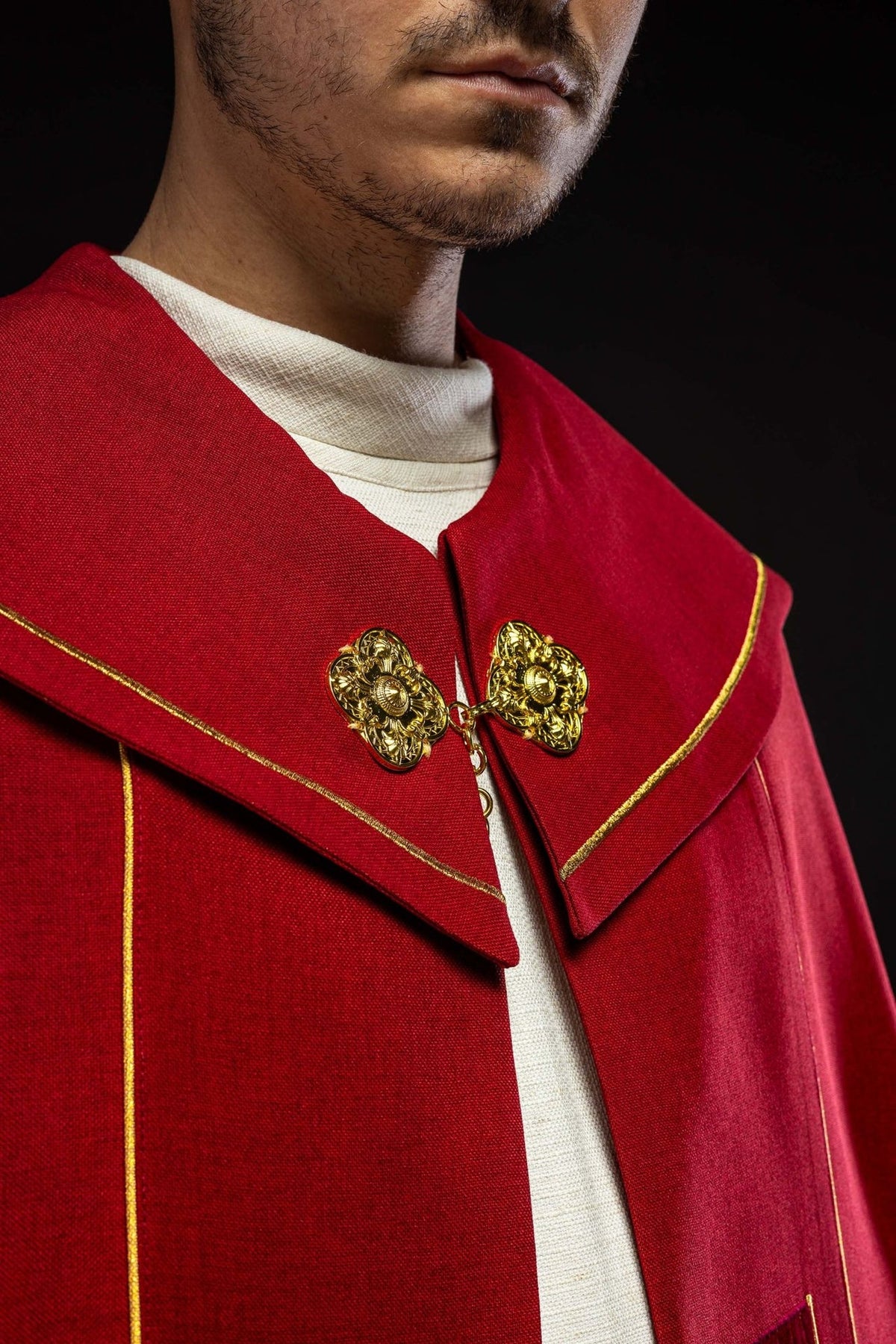 Red cope close-up showing embroidered gold cross and gold trim