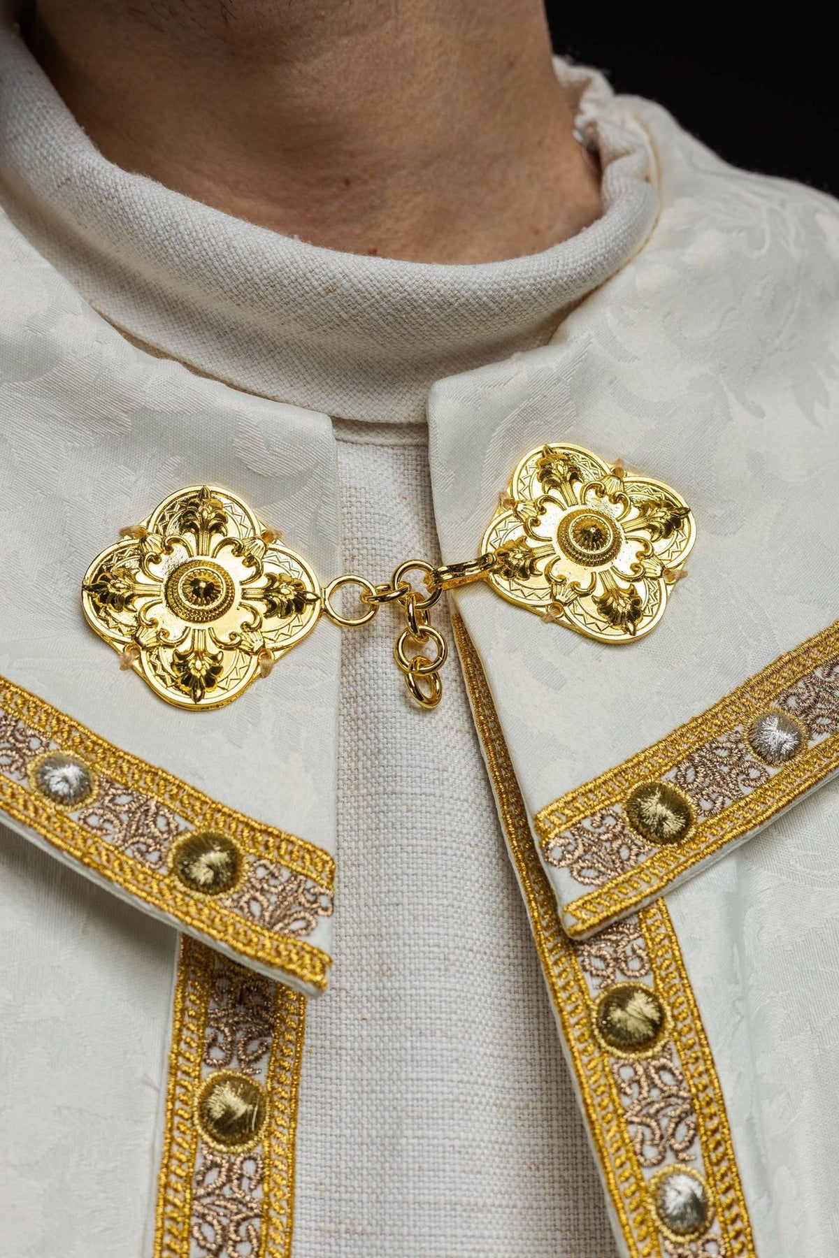 Ecru cope close-up showing cotton collar, jacquard fabric and gold clasp