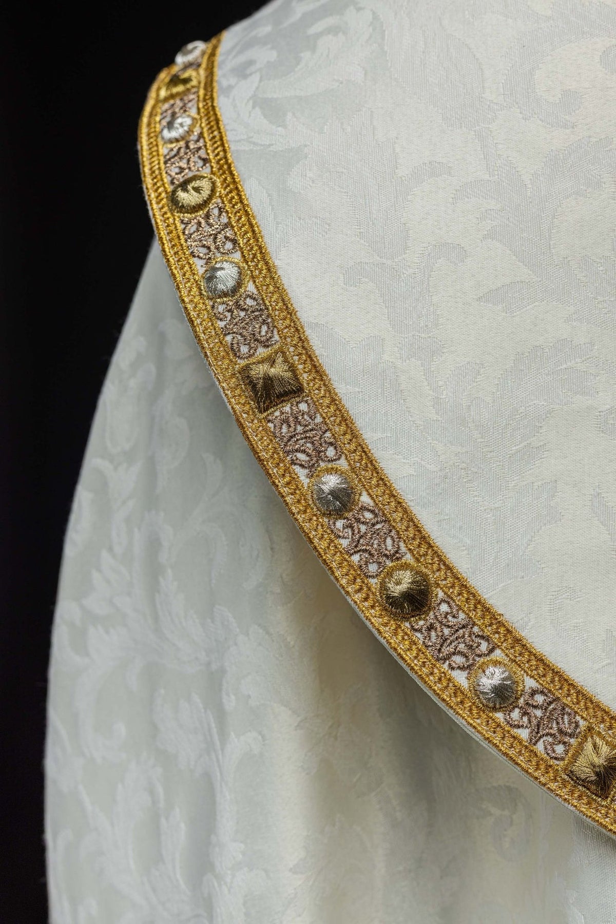 Ecru cope detail showing gold border, jacquard fabric and hanging tassel