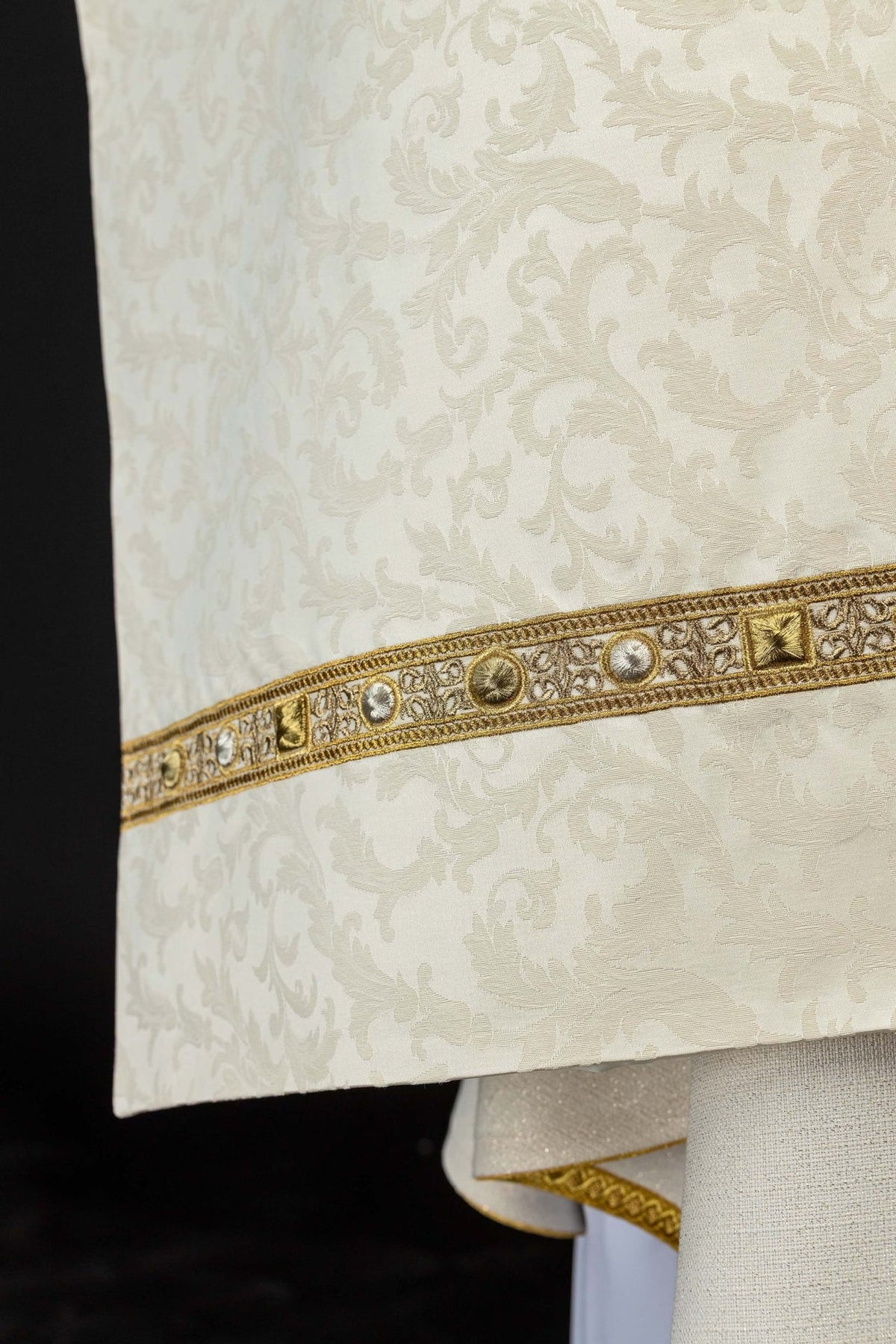 Humeral veil close-up showing ecru jacquard fabric with floral pattern and gold trim