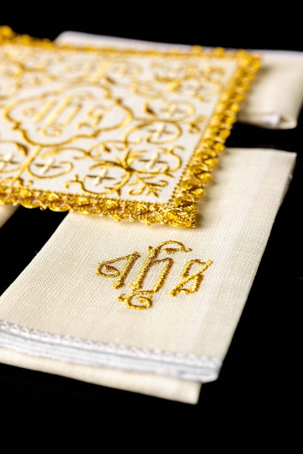 Altar linen set close-up showing gold embroidered JHS monogram and white stitched edging