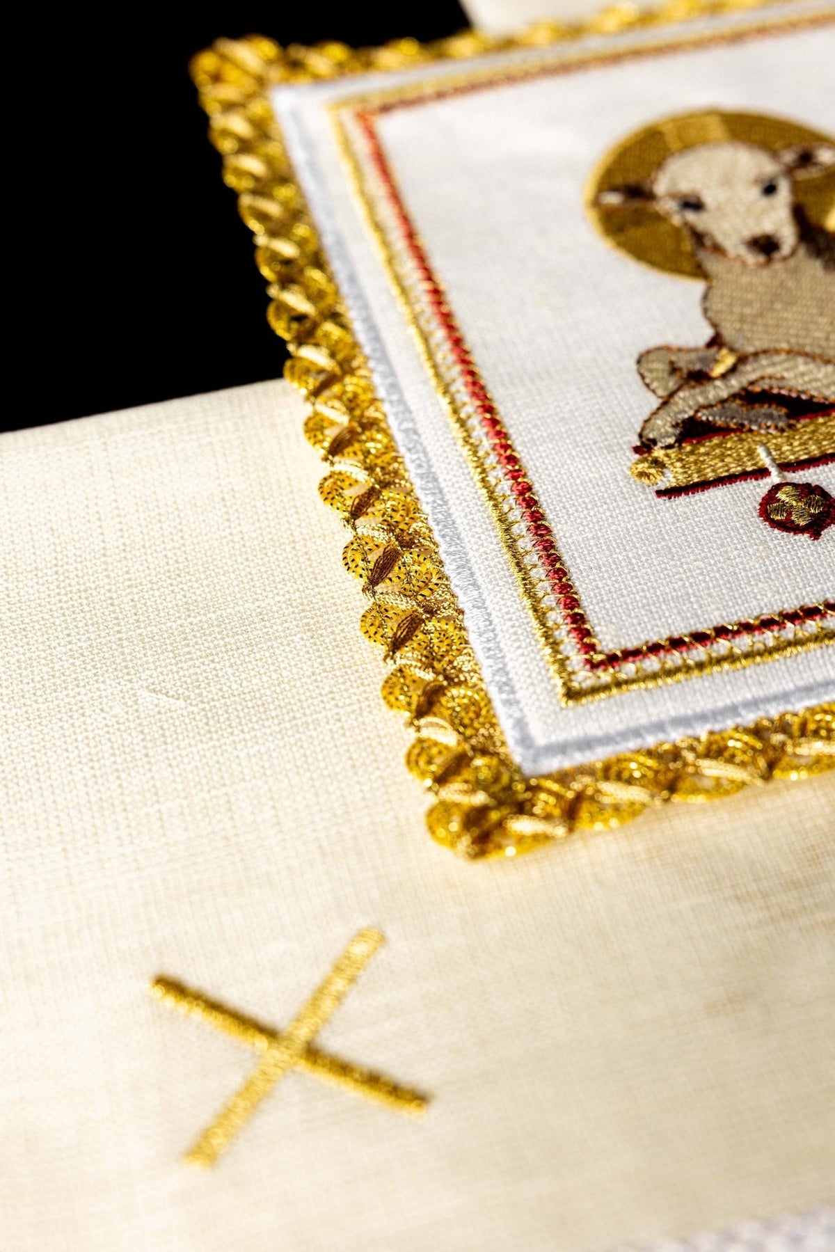 Altar linen set detail showing gold-trimmed lamb panel and white linen cloth with cross