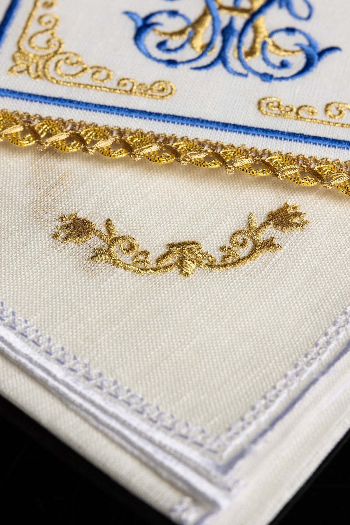 Altar linen close-up showing gold floral embroidery, blue edging and white stitched border