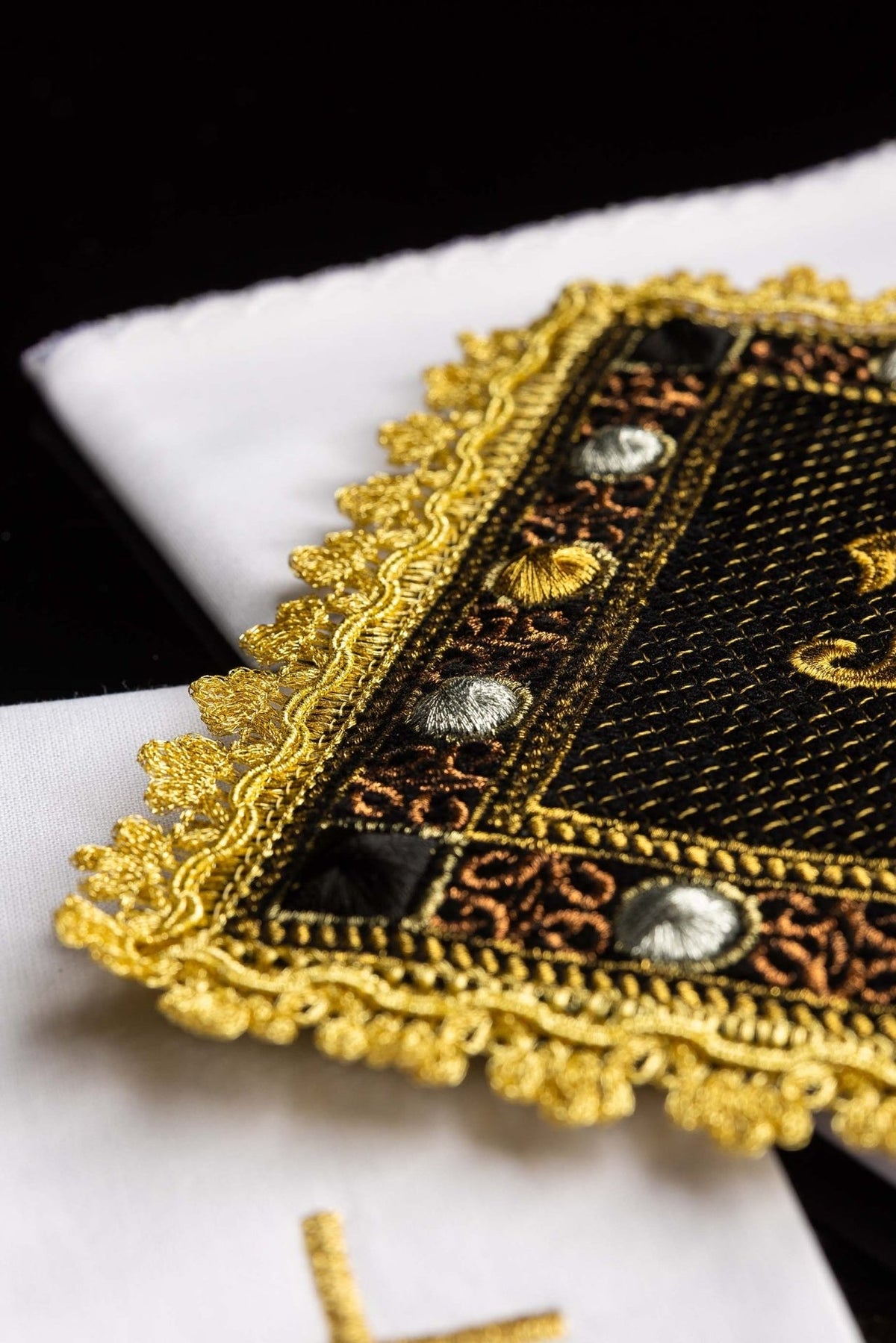 Black velvet chalice pall detail with gold embroidered border and multicolour decorative motifs