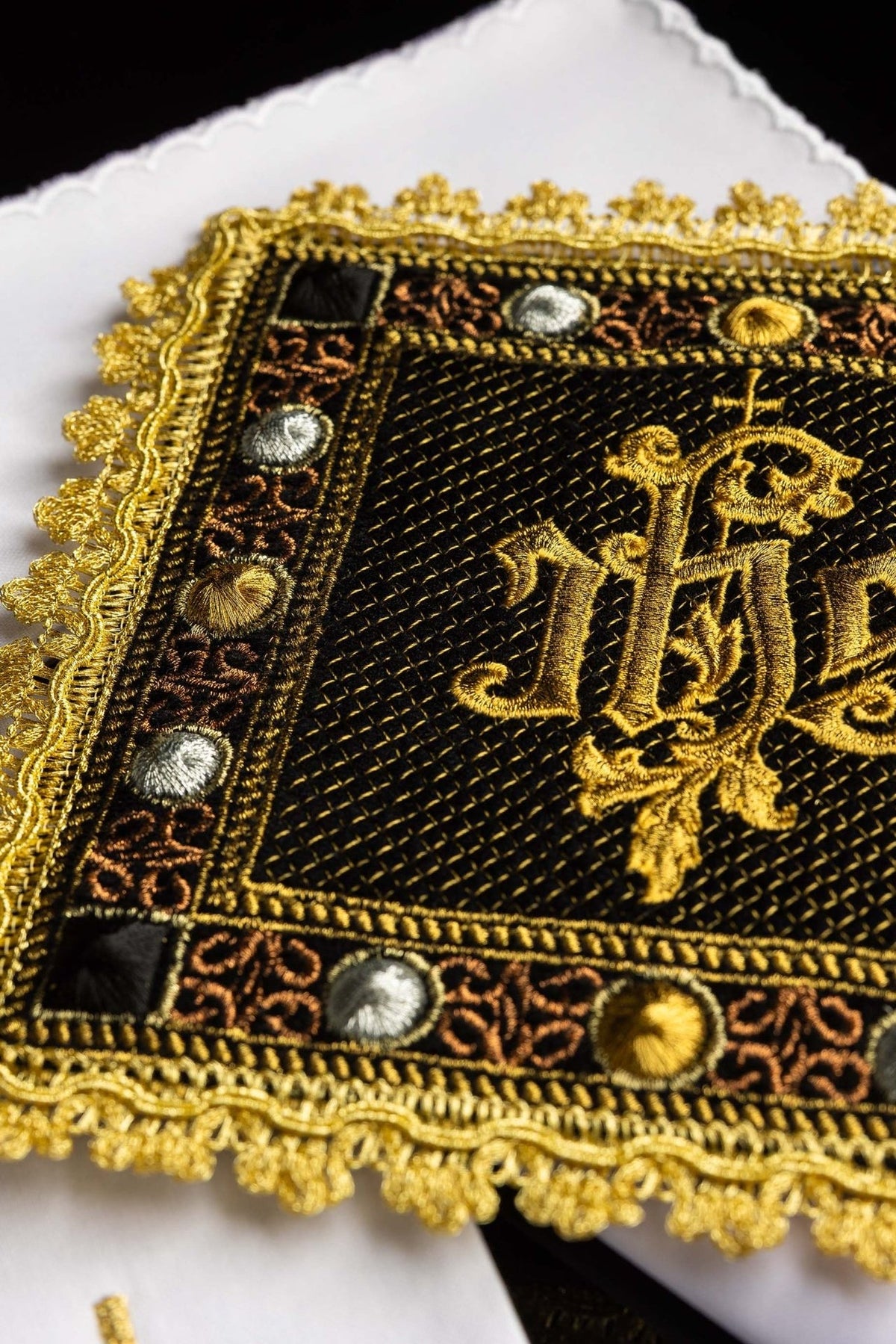 Embroidered IHS detail on black velvet chalice pall with gold ornamental border