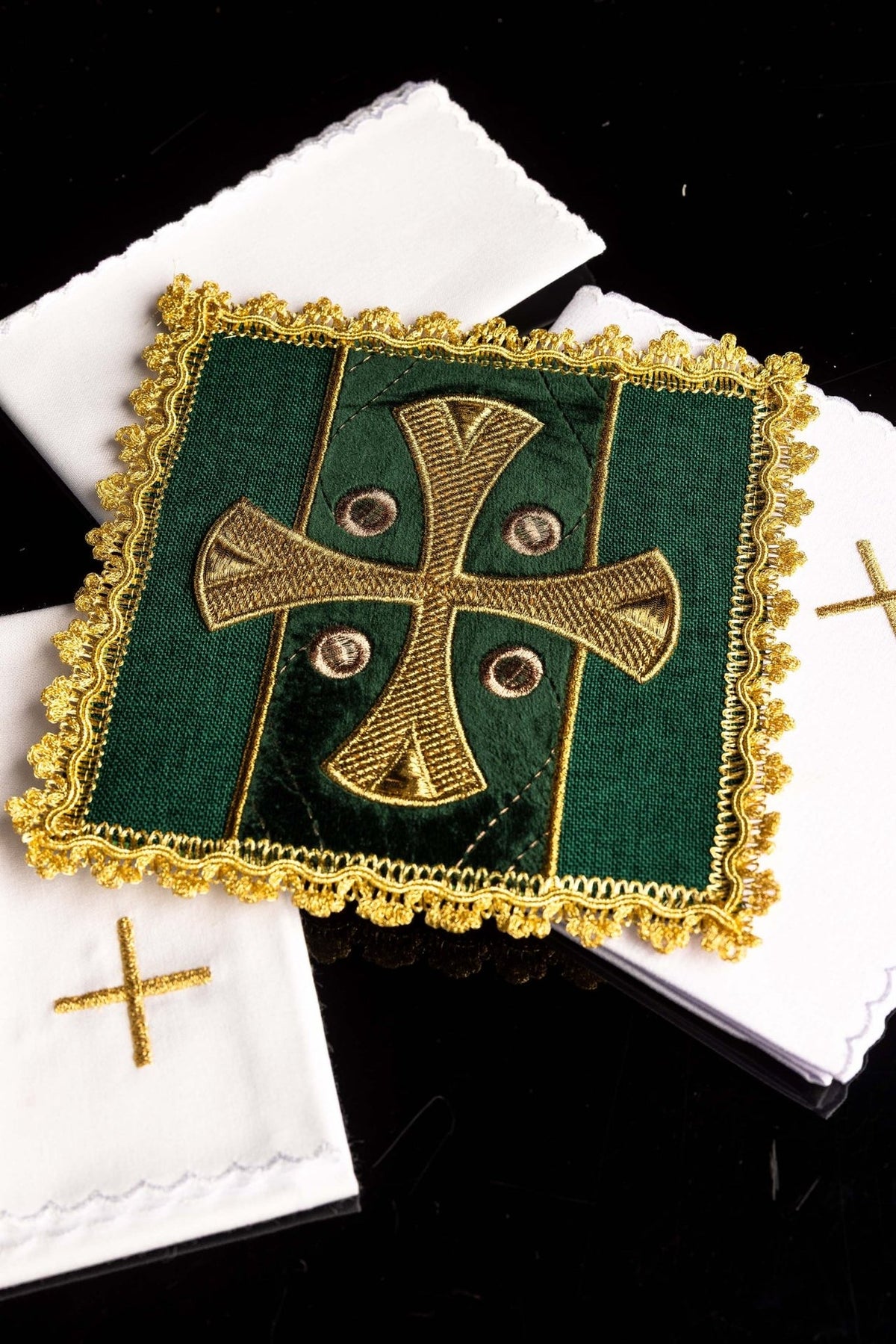 Embroidered velvet pall shown over white altar linens, with green fabric and gold cross