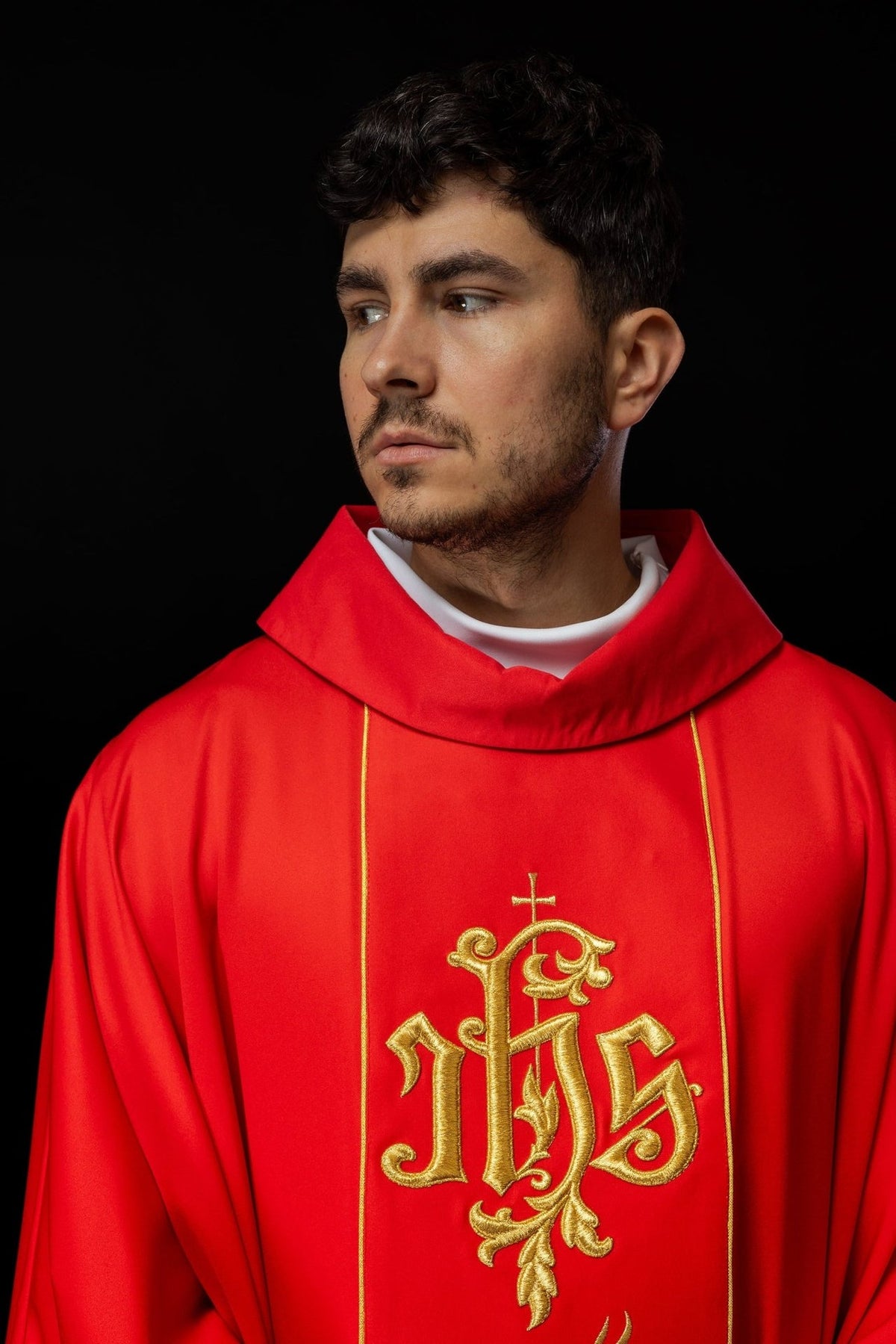 Red chasuble close-up showing stand-up collar and gold IHS embroidery