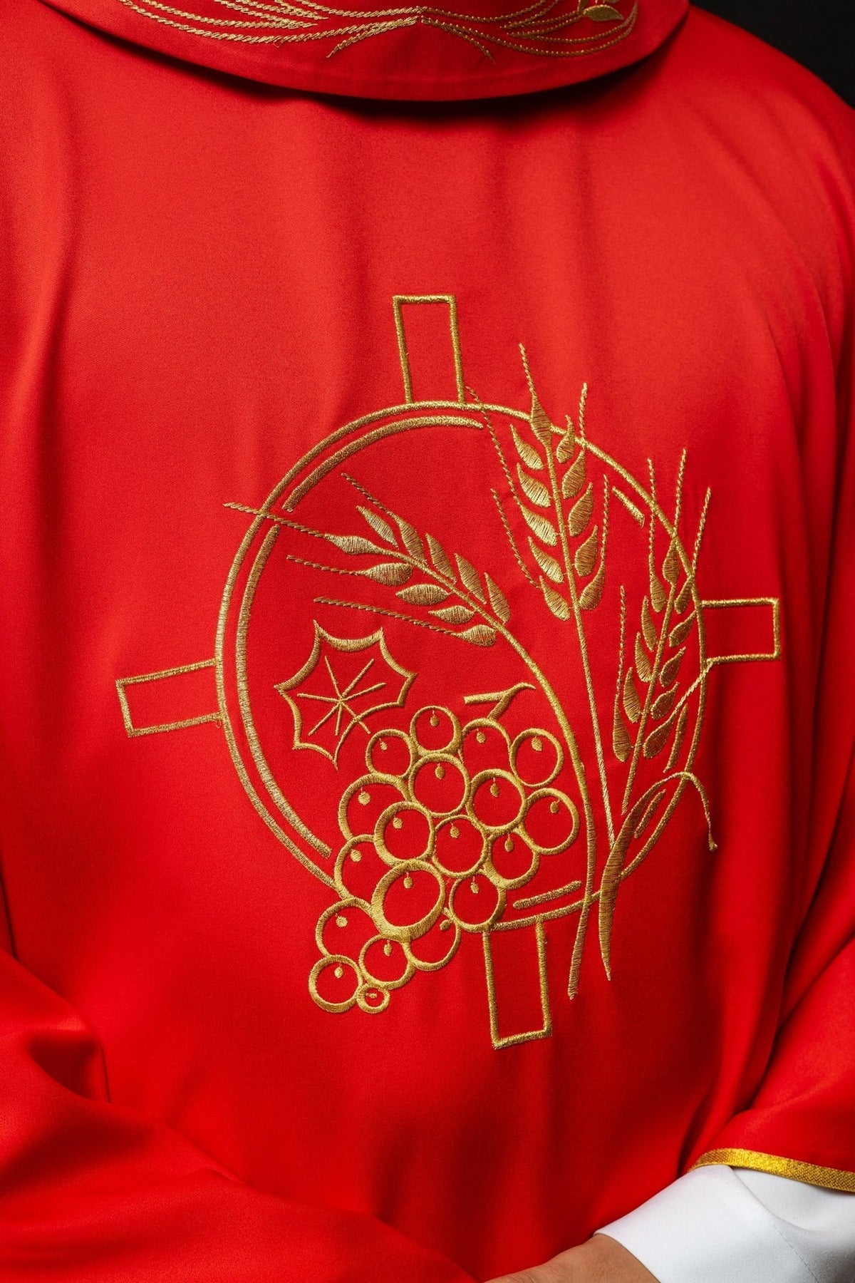 Red chasuble close-up showing embroidered gold cross, wheat and grape motifs