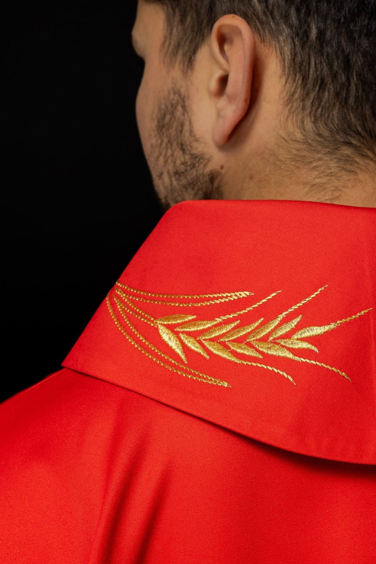 Red chasuble collar close-up with embroidered gold wheat motifs