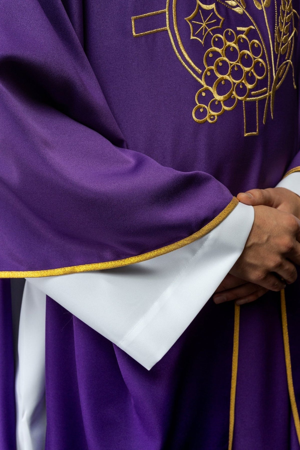 Purple chasuble close-up showing gold trim and embroidered cross motif