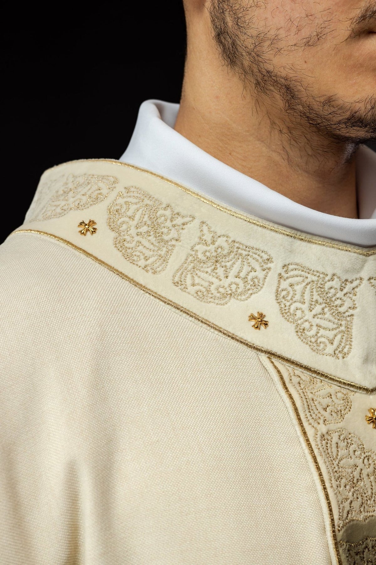 Ecru chasuble orphrey close-up with gold cross details and fringe