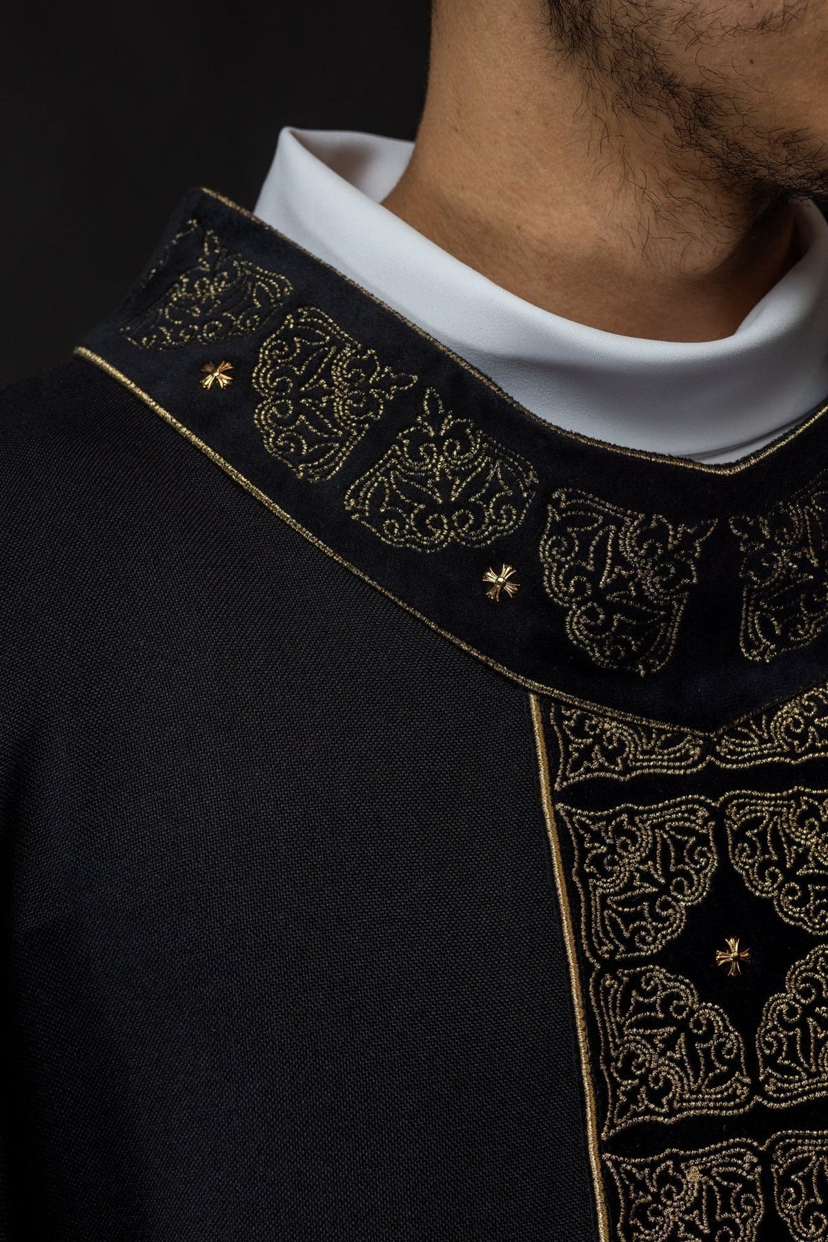 Black chasuble close-up showing gold embroidery on the lower orphrey
