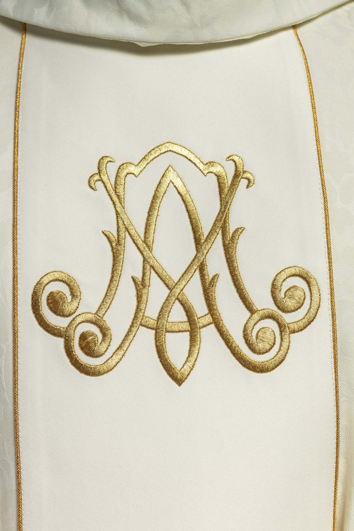 Chasuble close-up of gold embroidered Marian monogram on the front panel