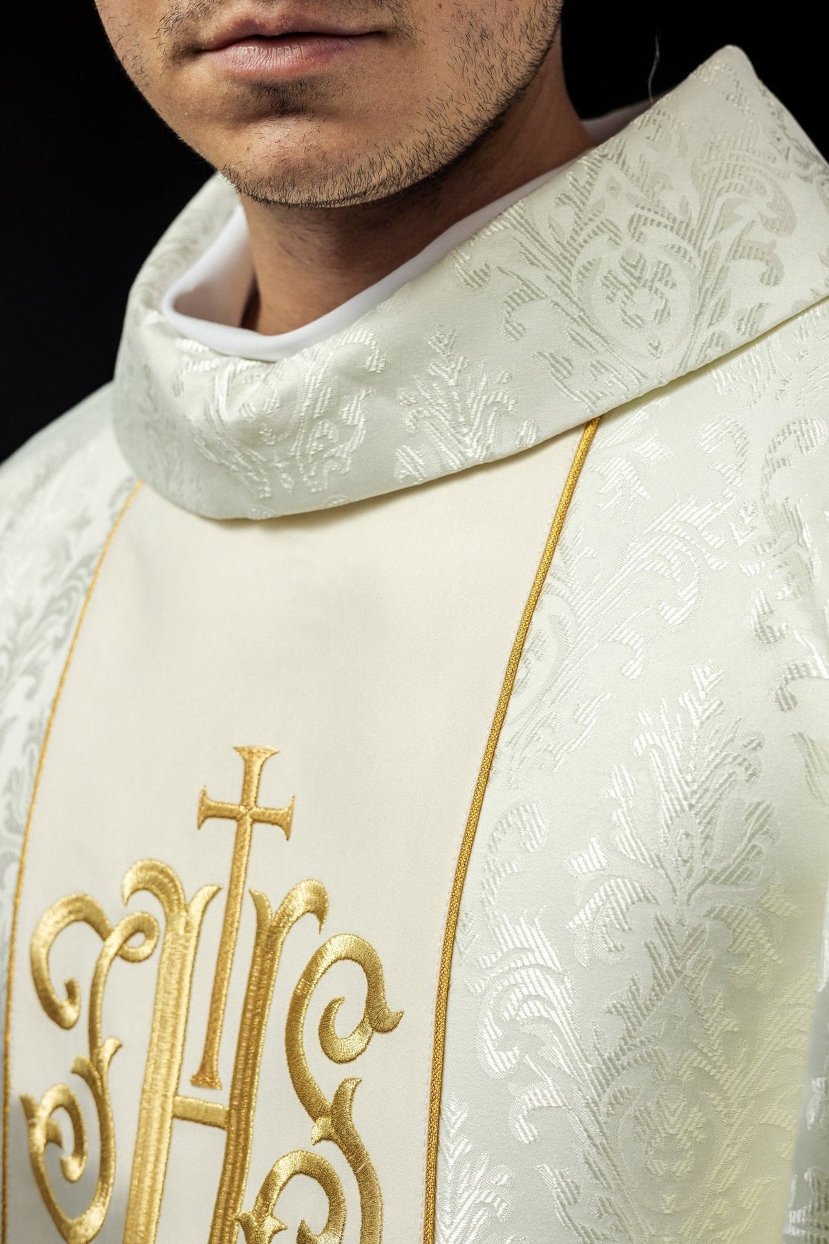 Ecru chasuble side close-up showing patterned fabric, gold trim and wide sleeve