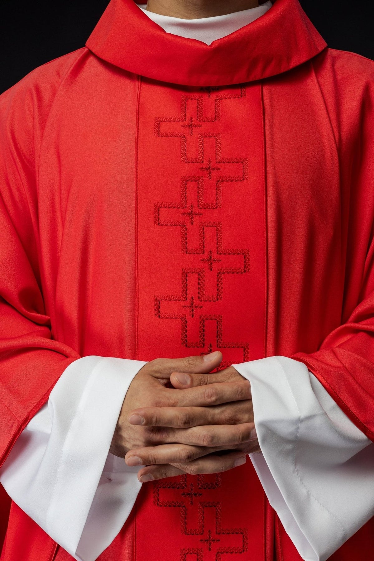 Red chasuble close-up showing cross embroidery on the front orphrey