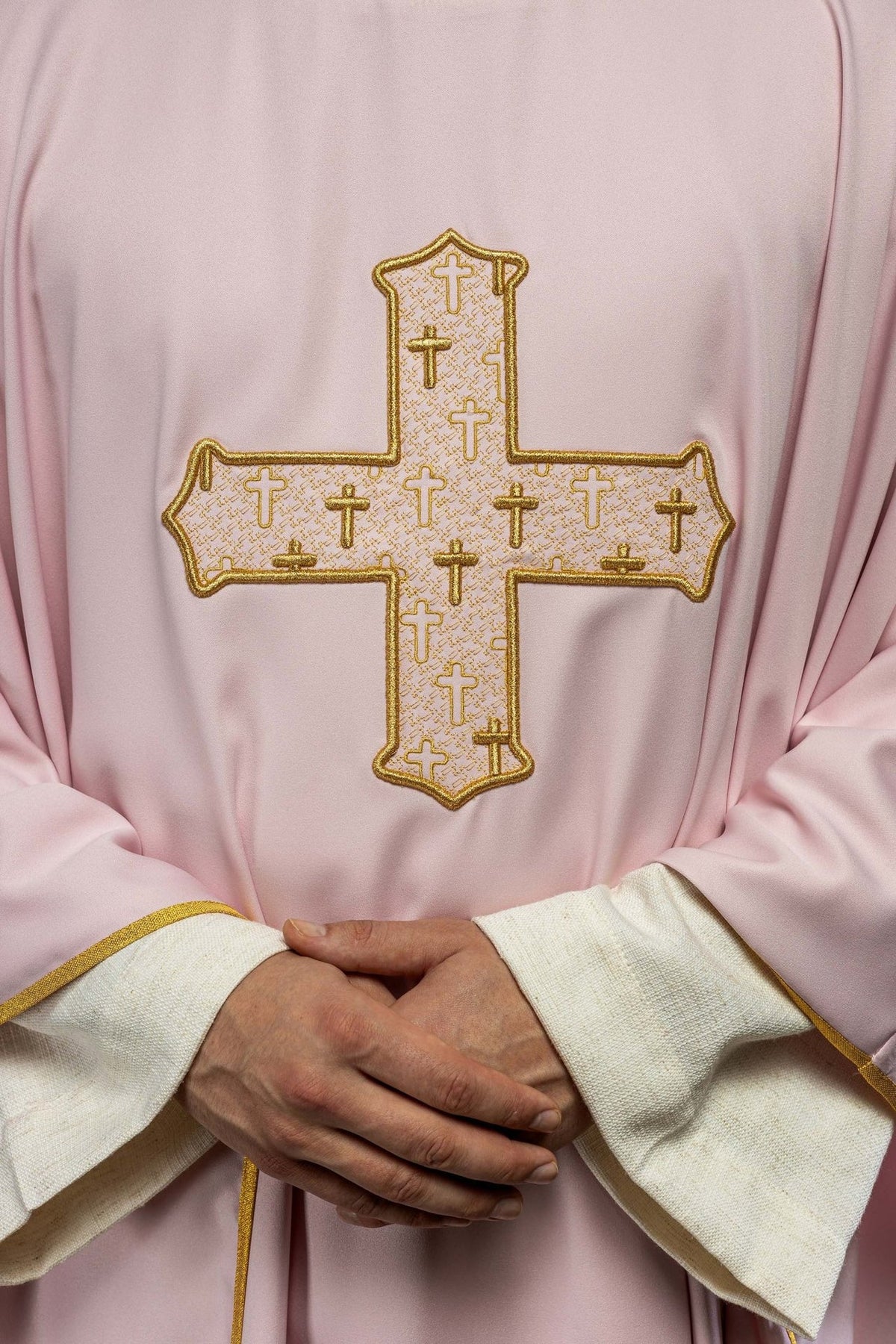 Rose chasuble close-up showing the richly embroidered gold cross